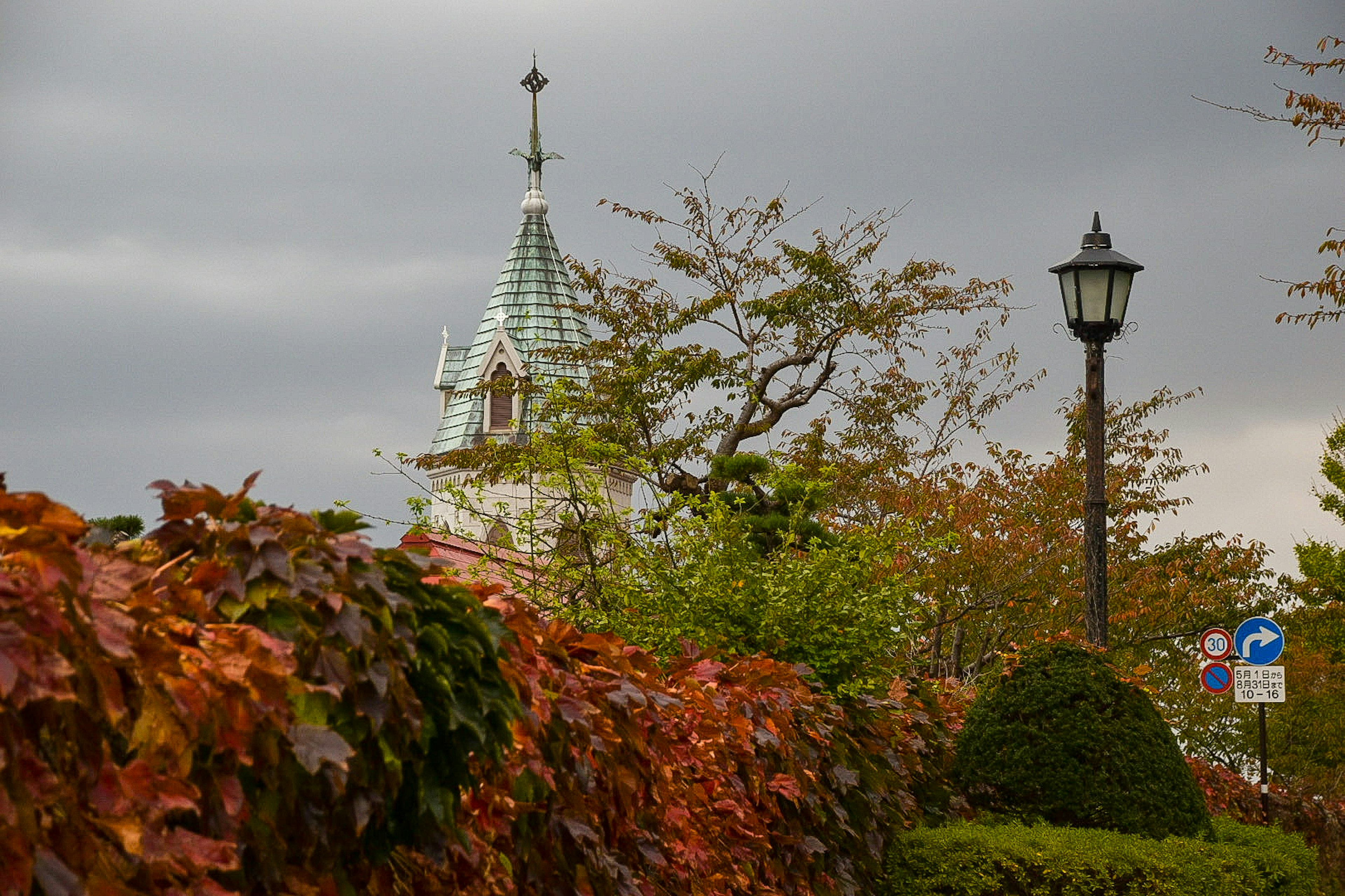 Beautiful tower of a building surrounded by autumn foliage and a street lamp