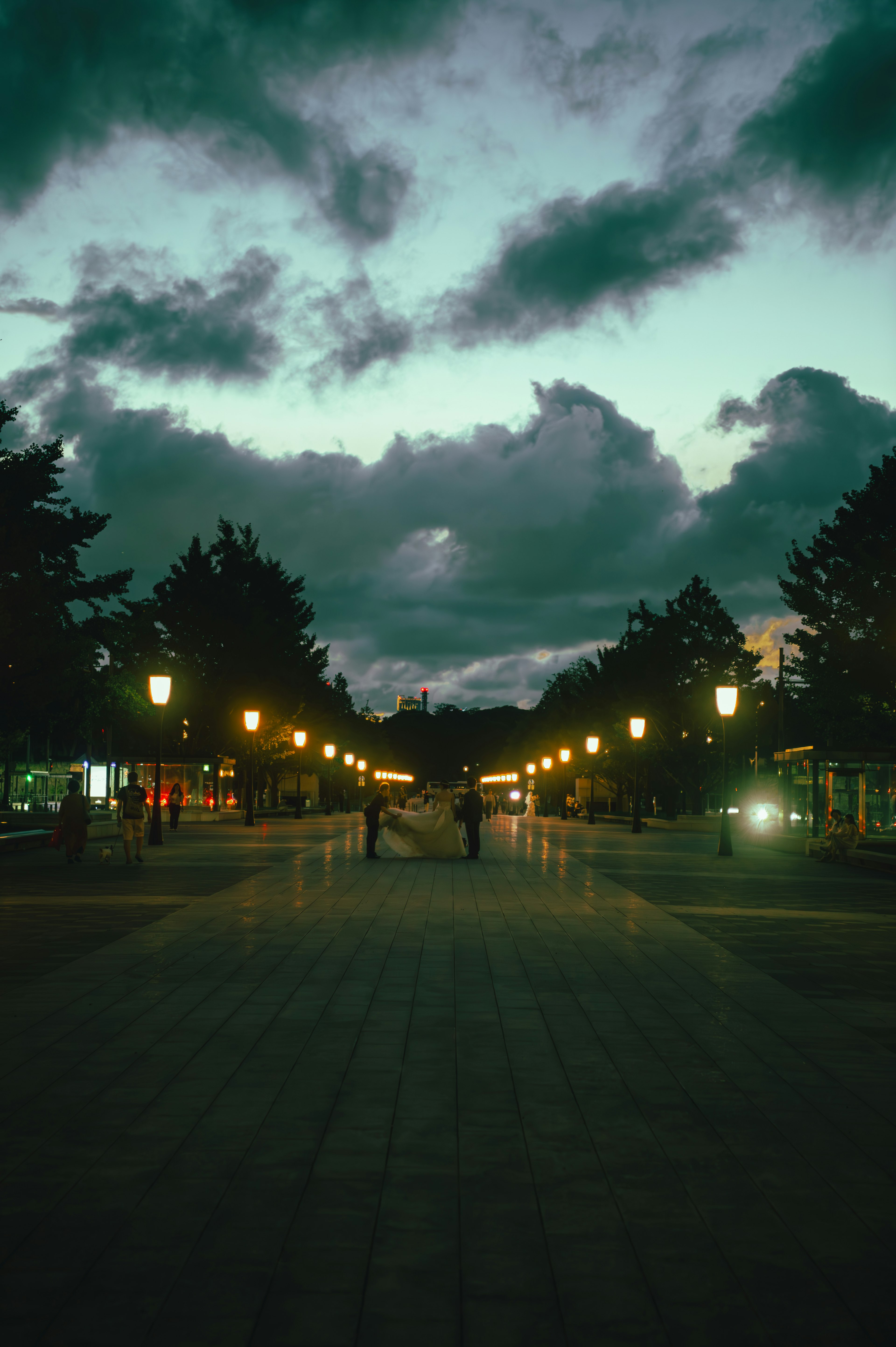 Scène de rue au crépuscule avec des lampadaires illuminés et des nuages dramatiques