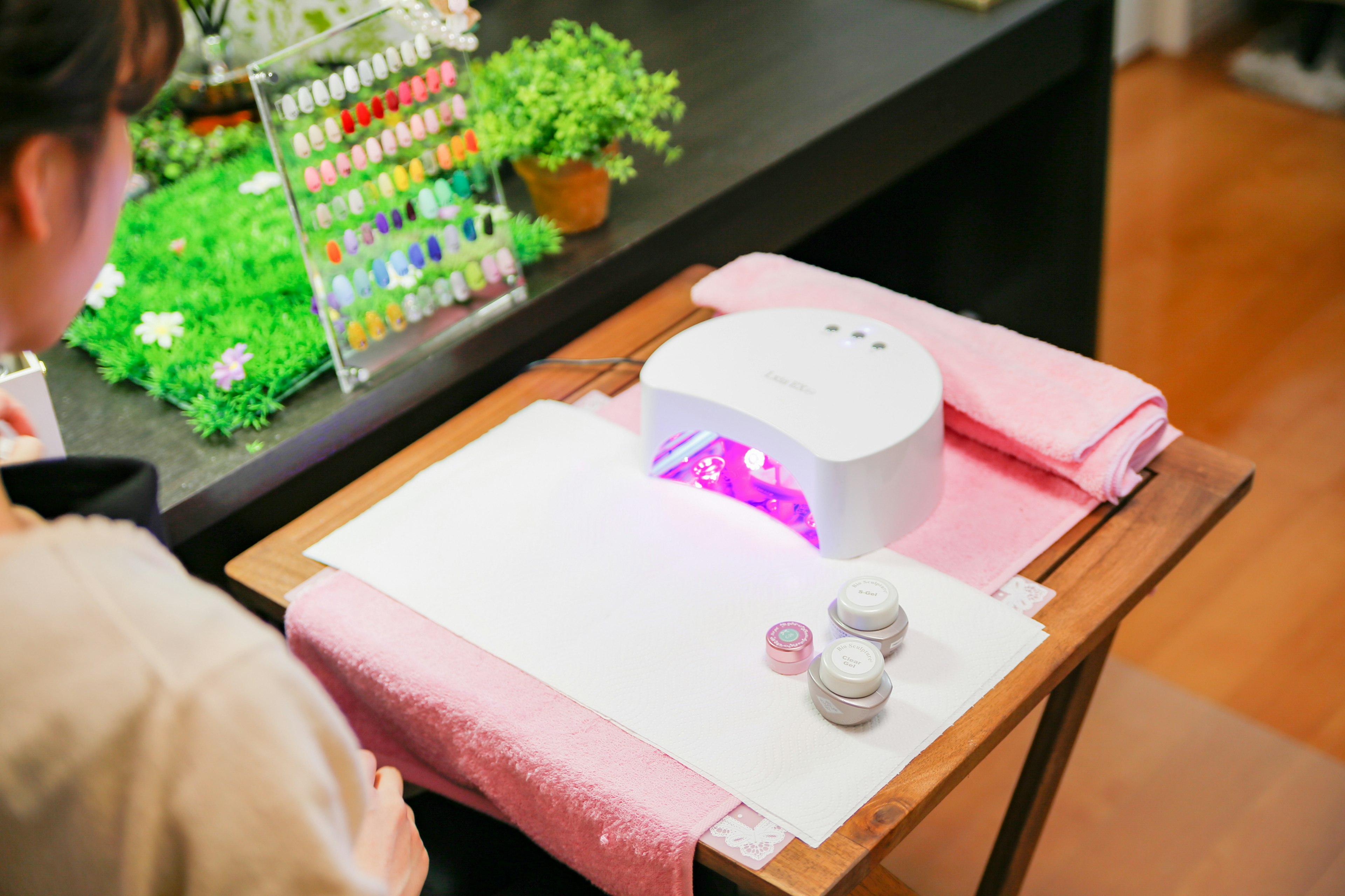 Woman receiving gel nail treatment with UV lamp in nail salon