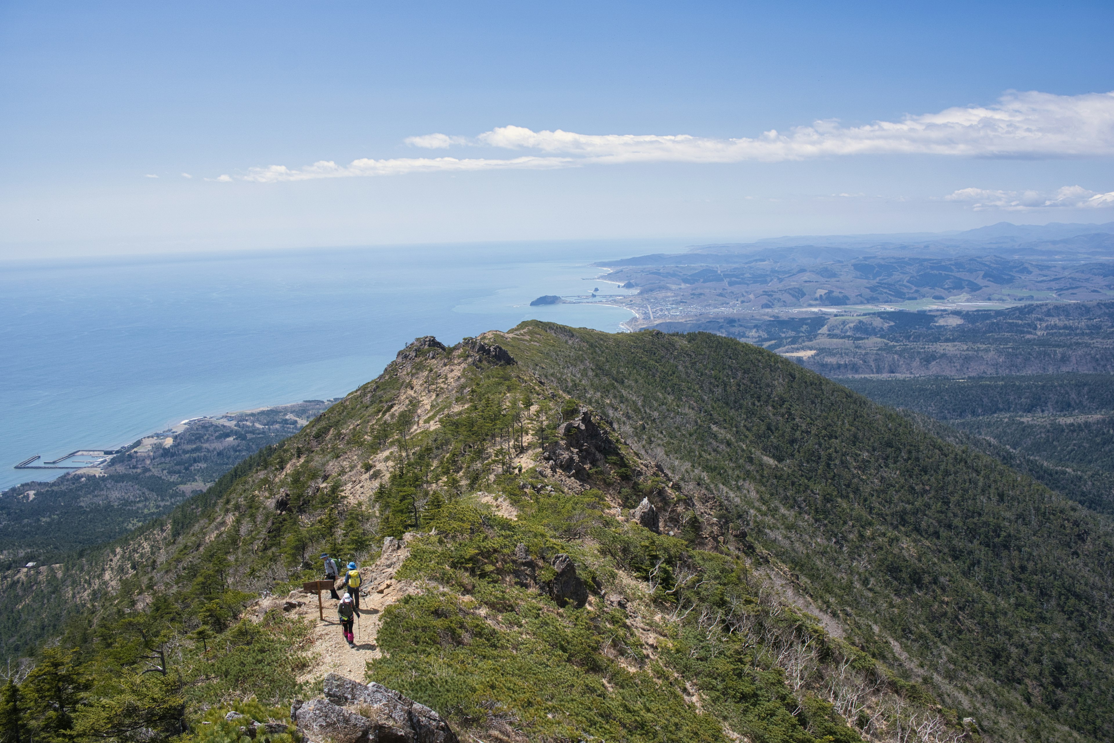 Vista desde la cima de la montaña sobre el océano y una persona caminando por el sendero