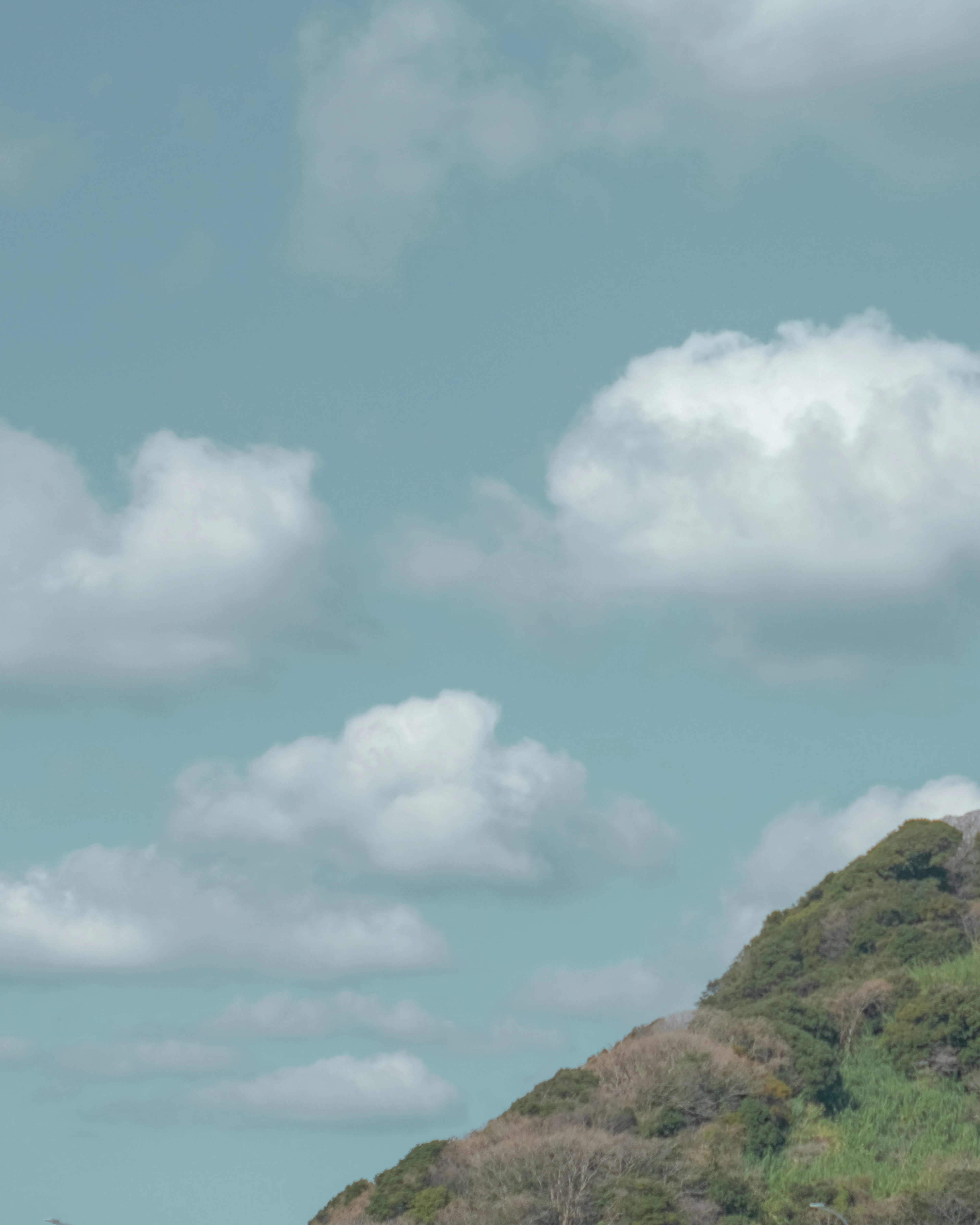 Langit biru dengan awan putih dan bukit hijau