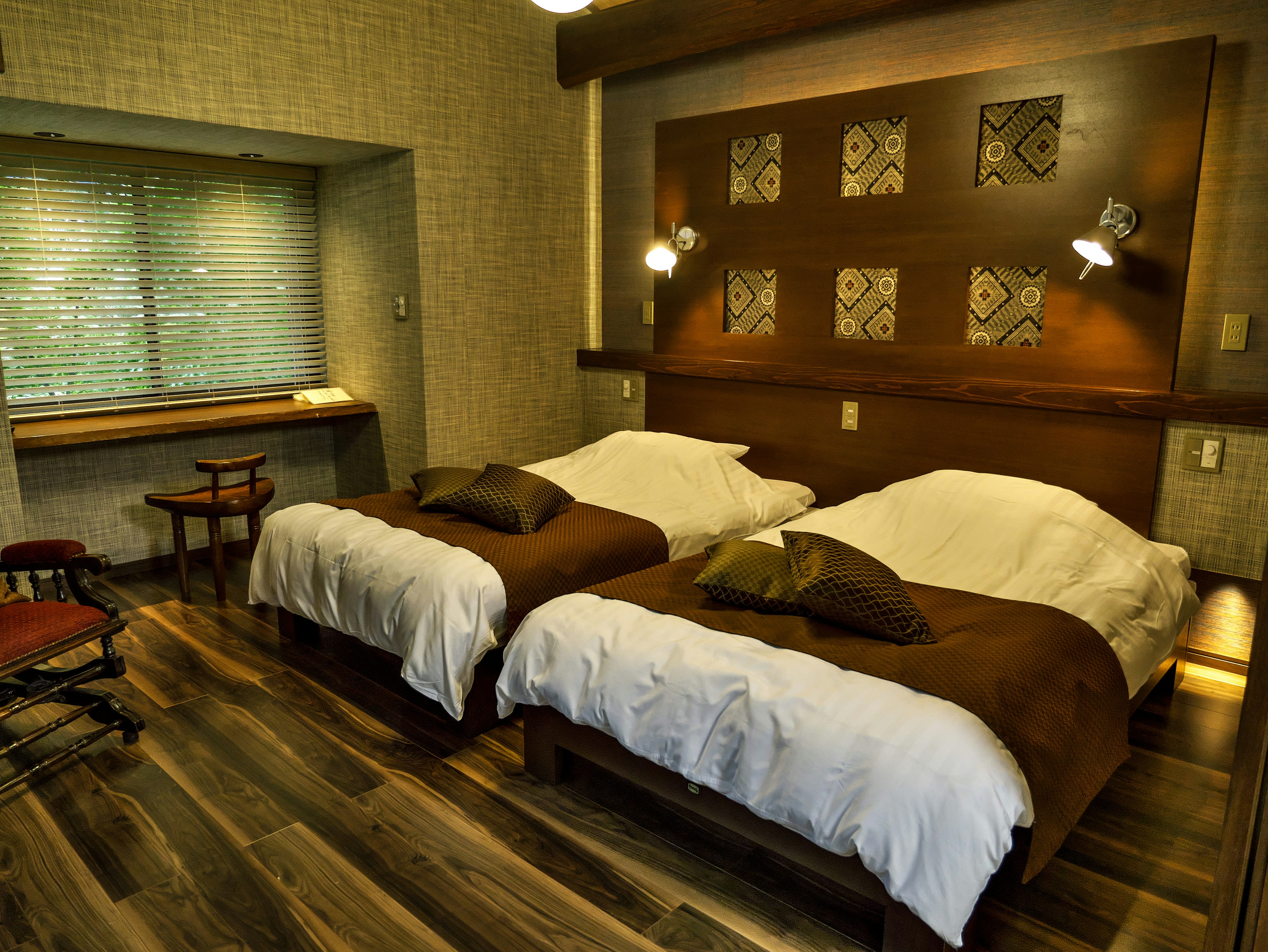 Simple modern bedroom with two beds and wooden flooring natural light coming through the window