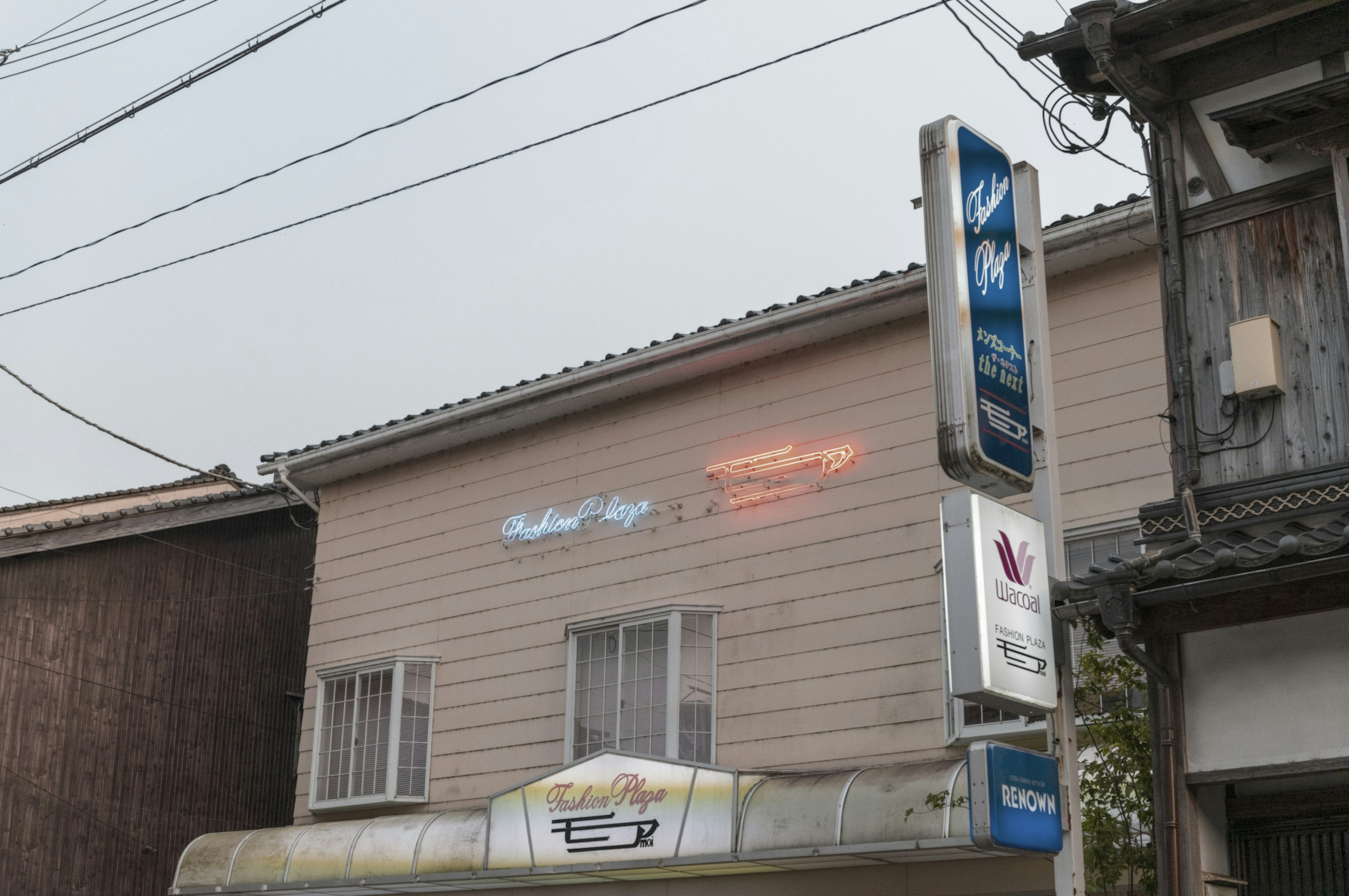 外壁に看板がある店舗の写真 電線が張り巡らされた街並み