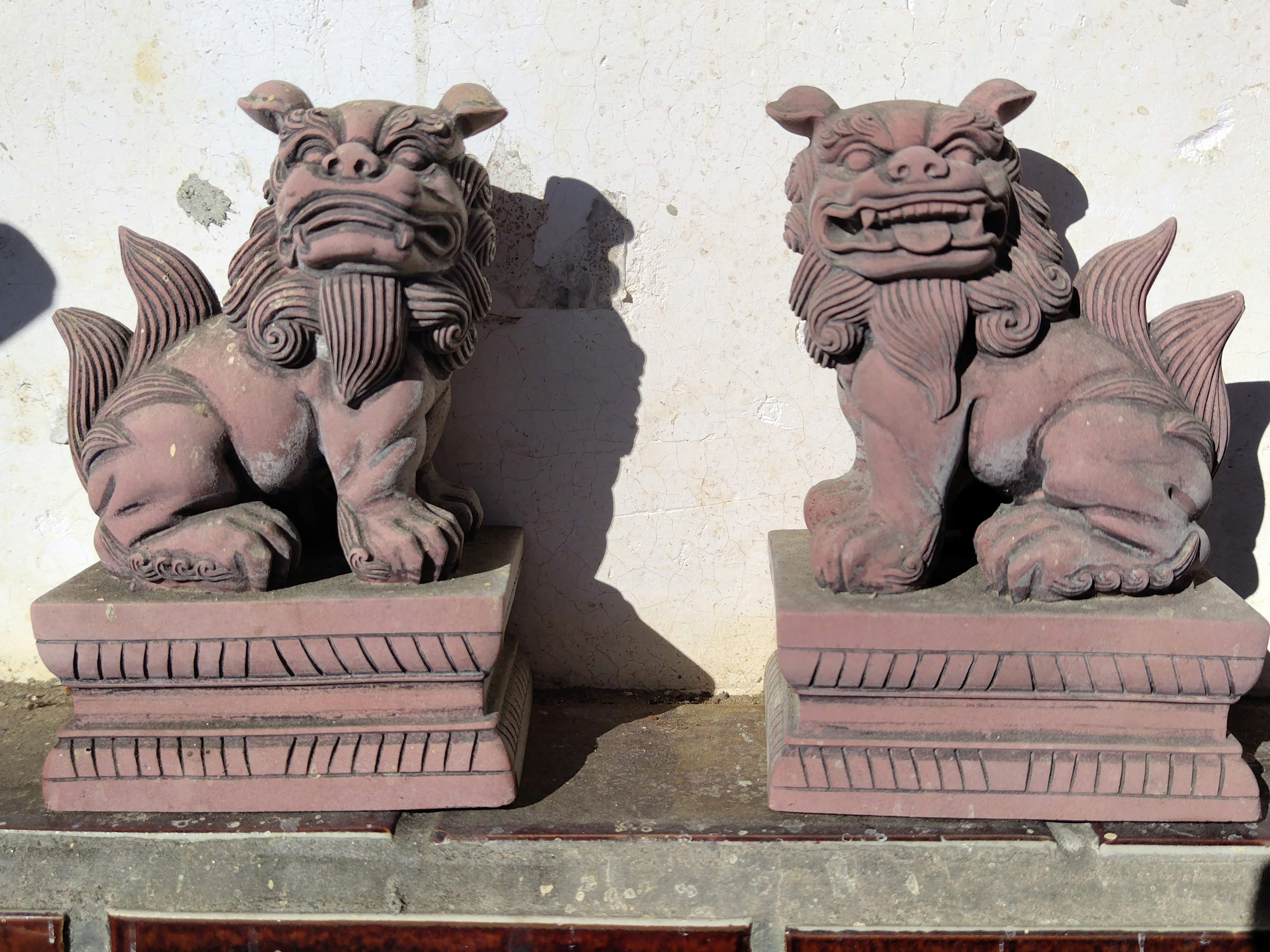 Deux sculptures de lions sur des socles avec des détails complexes