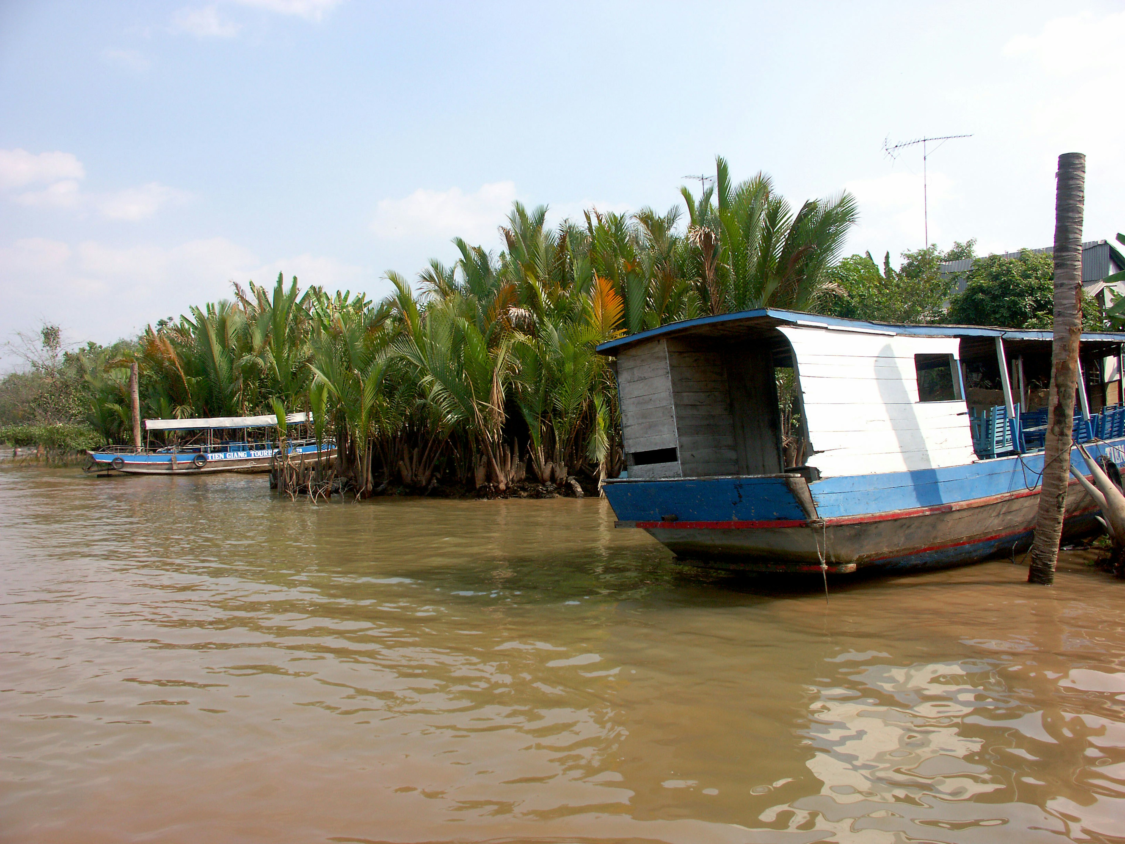 Perahu berlabuh dekat sungai dikelilingi oleh vegetasi subur