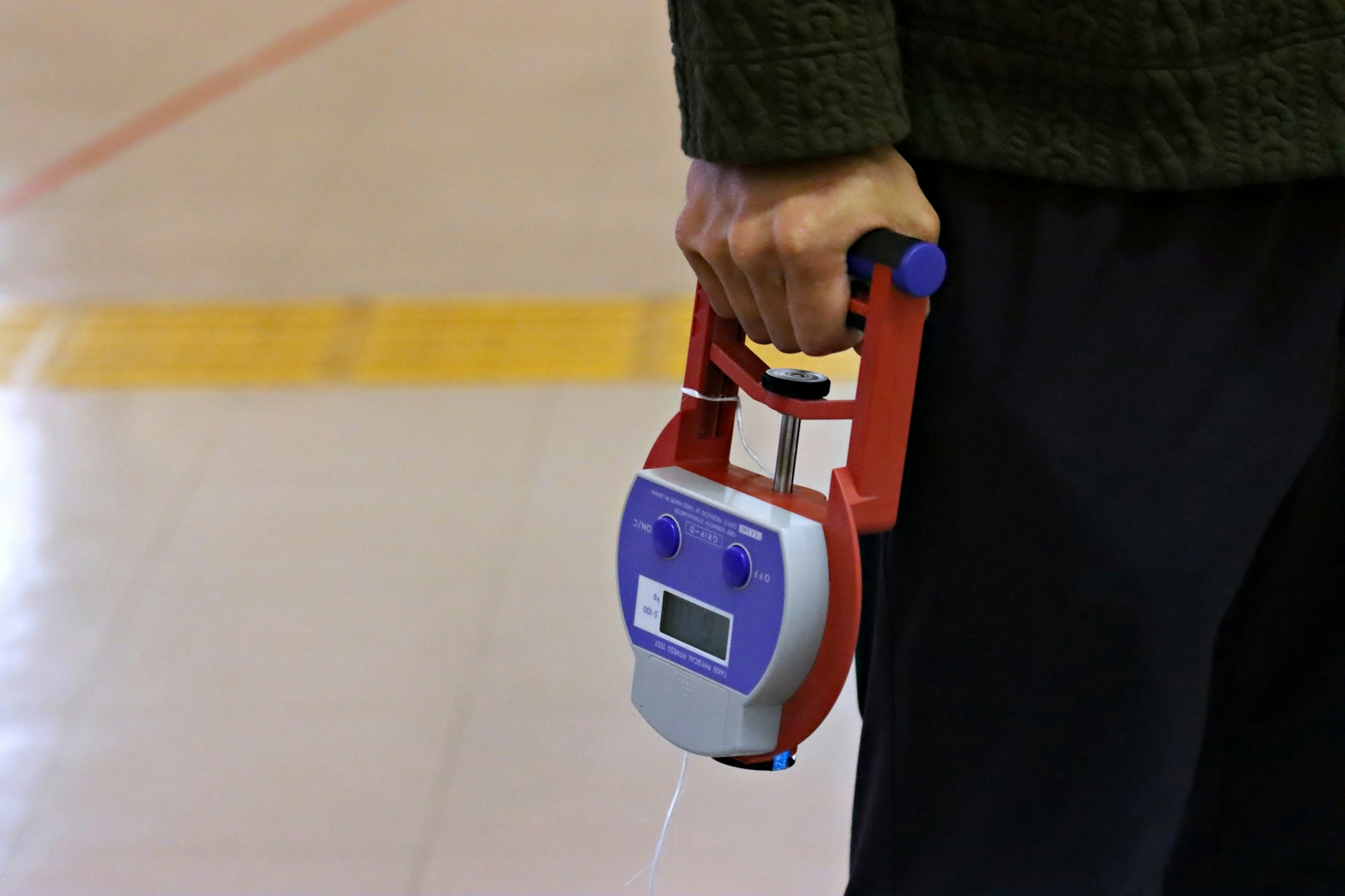 A person holding a handheld red and blue device