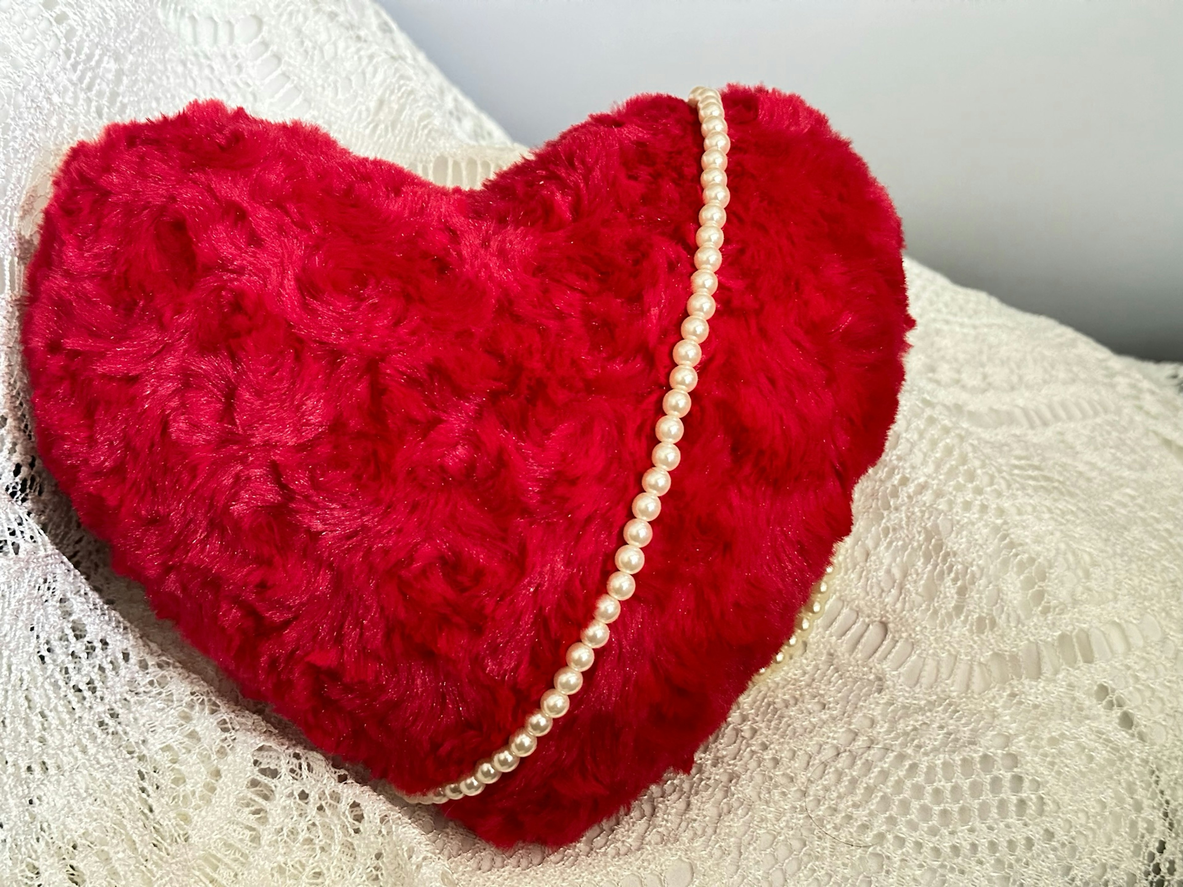 Red heart-shaped cushion adorned with a pearl decoration