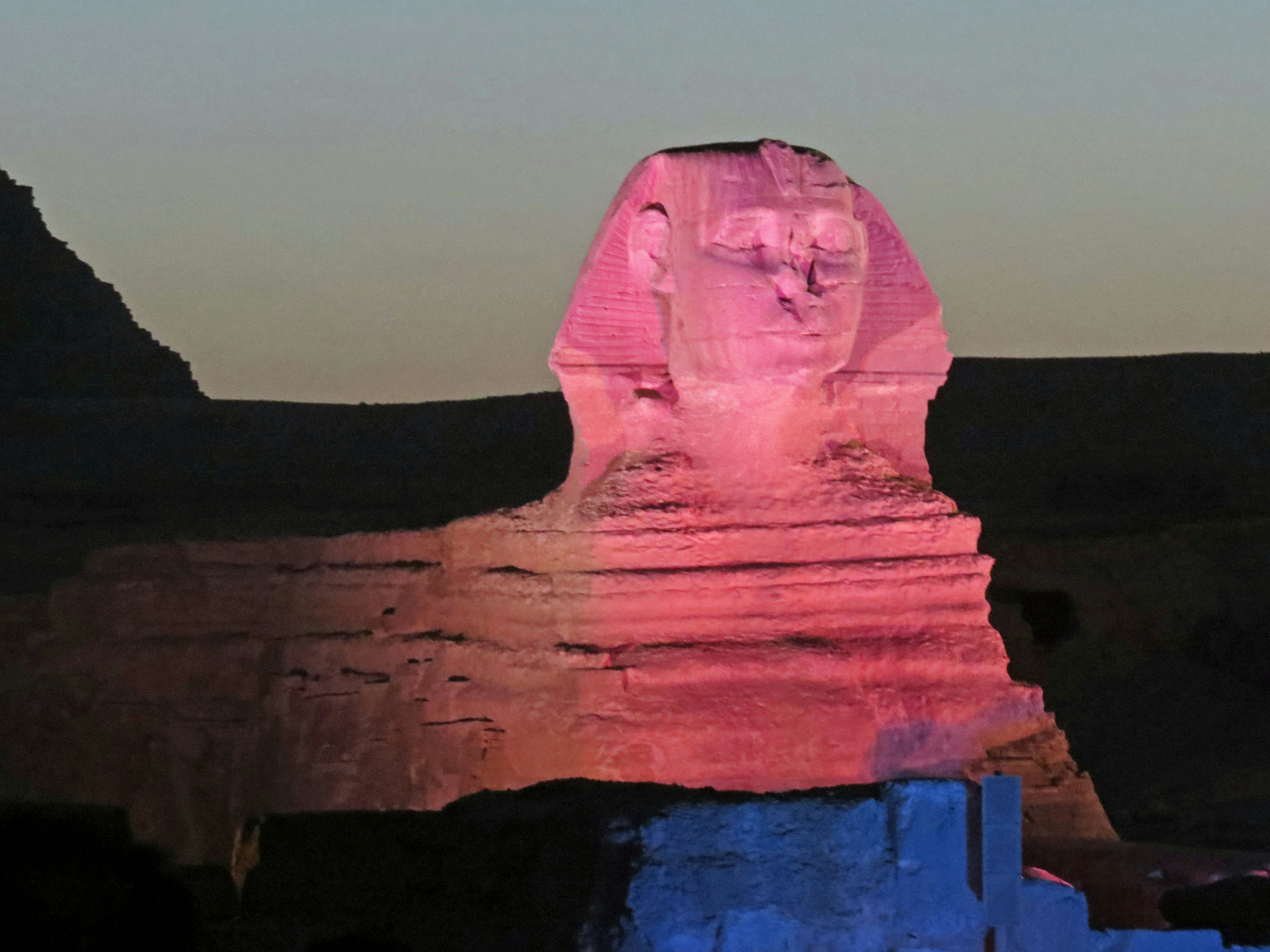 Esfinge iluminada en rosa y azul contra un cielo crepuscular