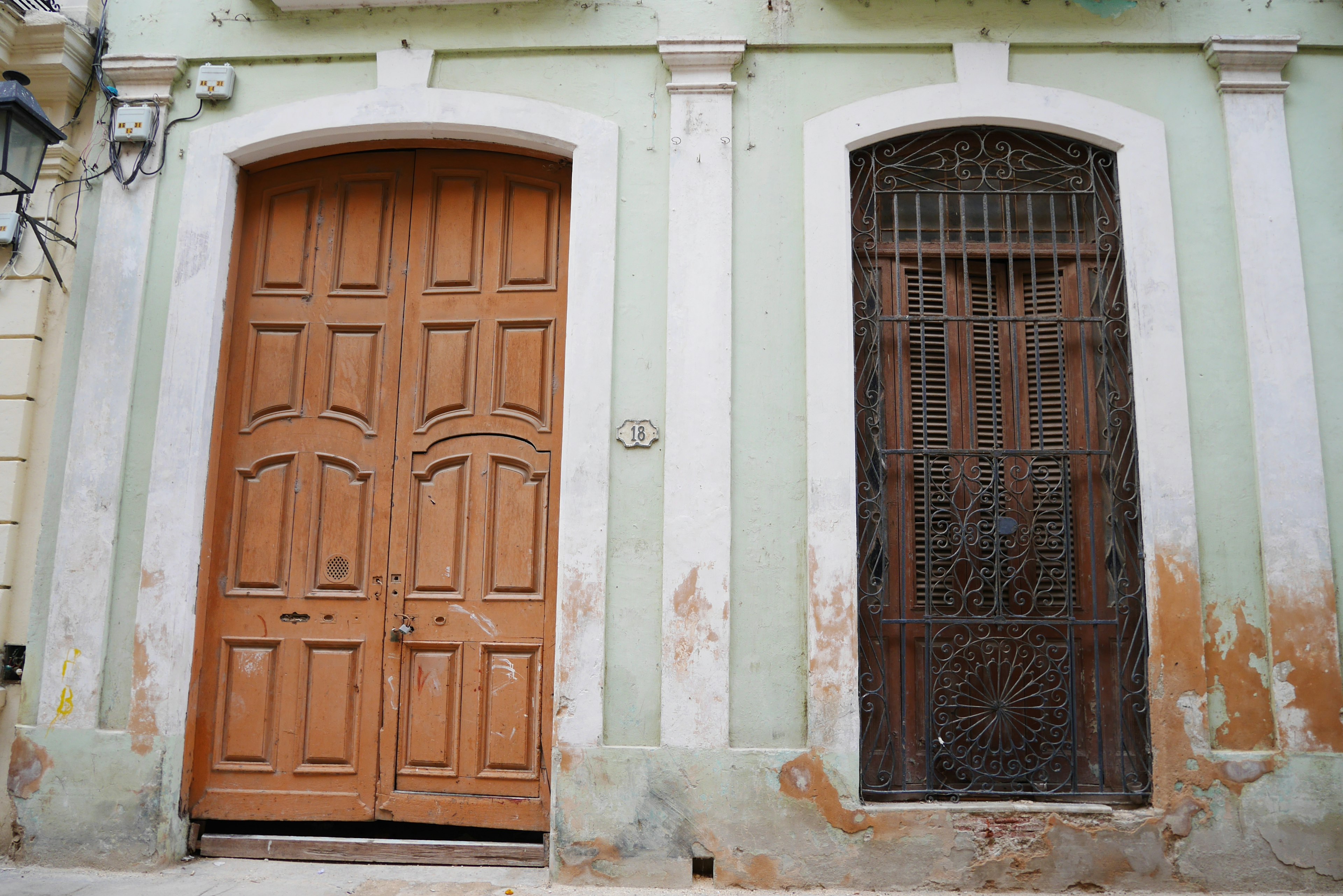 Fachada de un edificio antiguo con una puerta de madera y una reja de hierro forjado