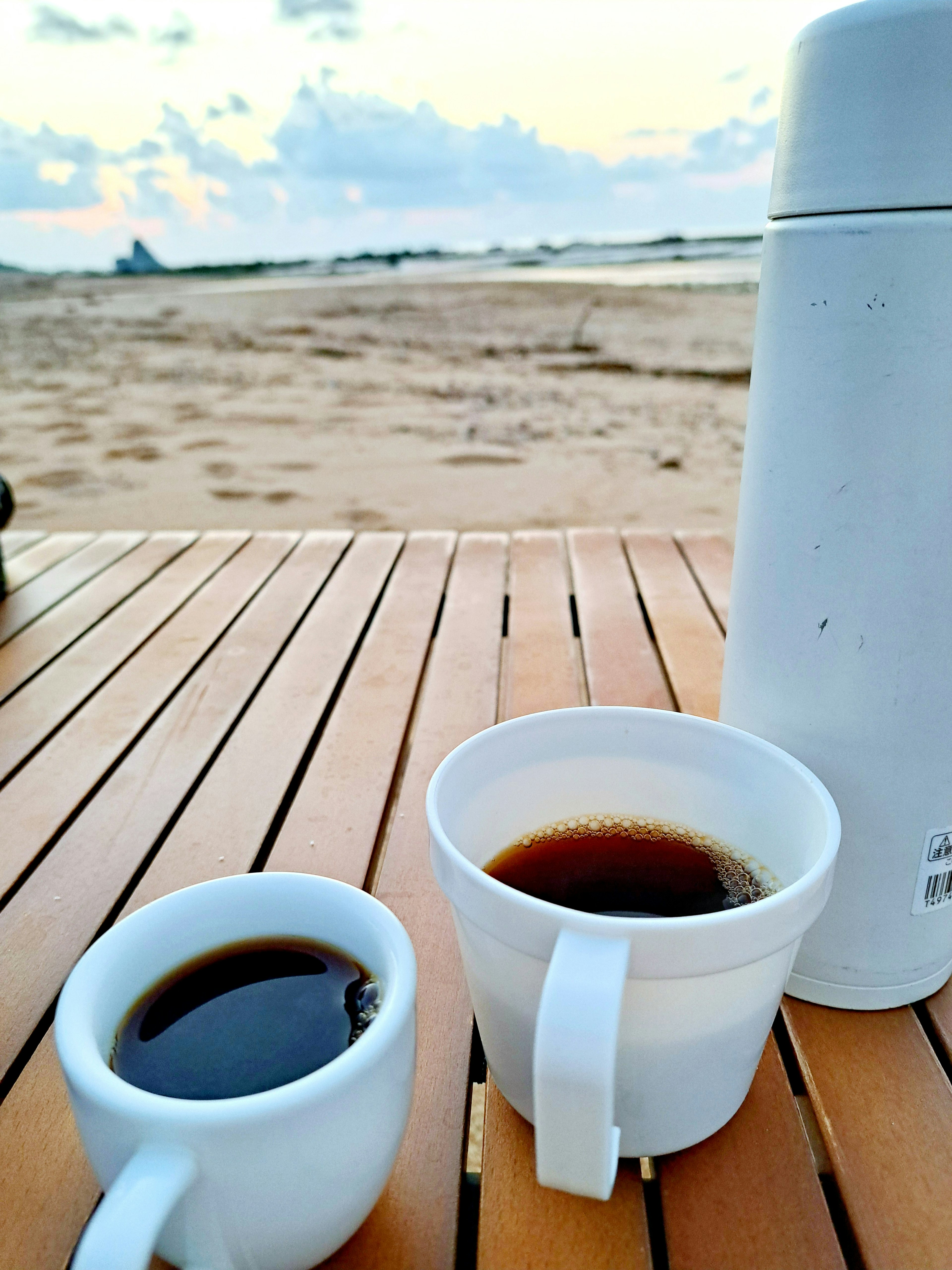 Tazze di caffè su un tavolo di legno con sfondo di spiaggia