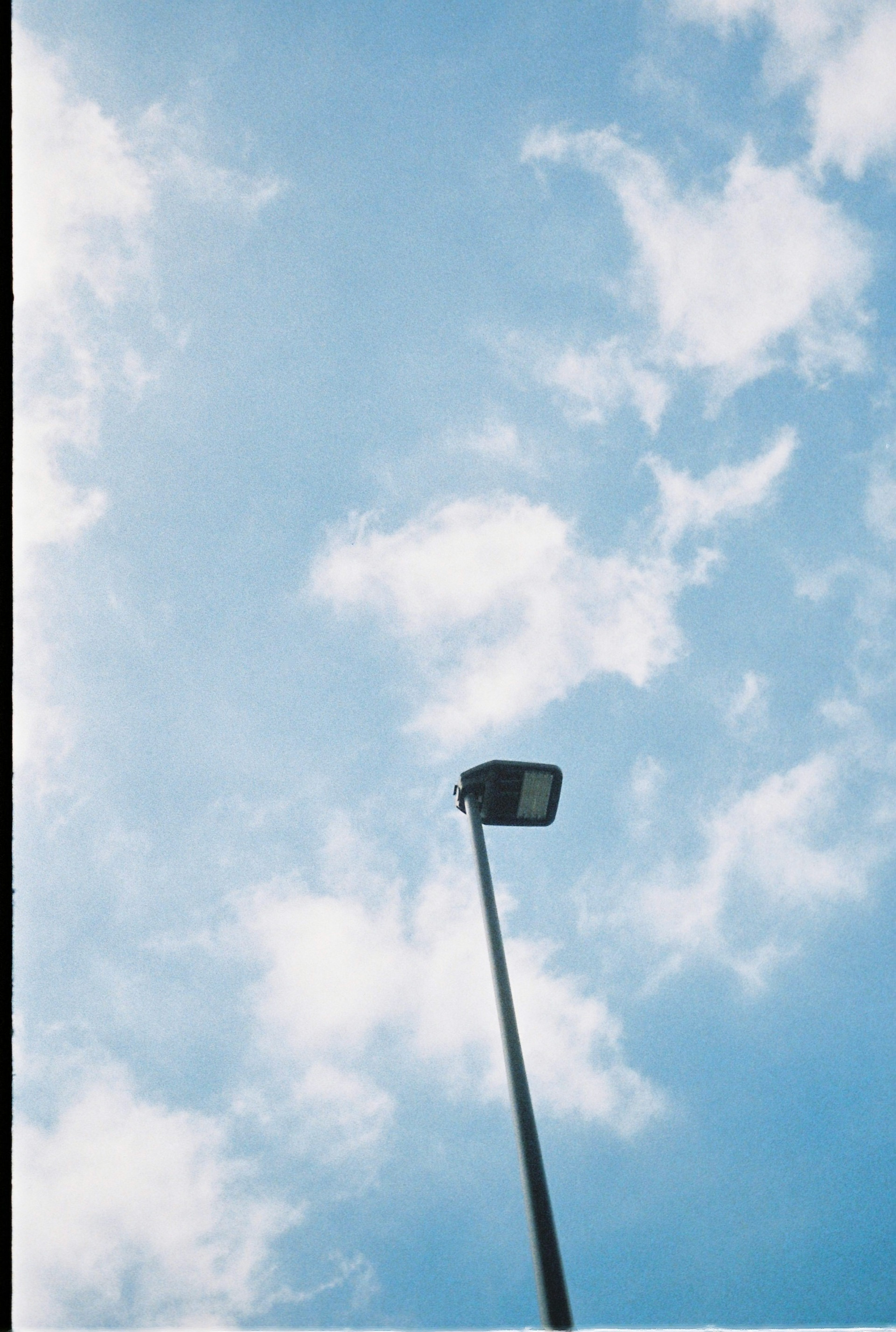 Foto einer Straßenlaterne vor einem blauen Himmel mit verstreuten Wolken