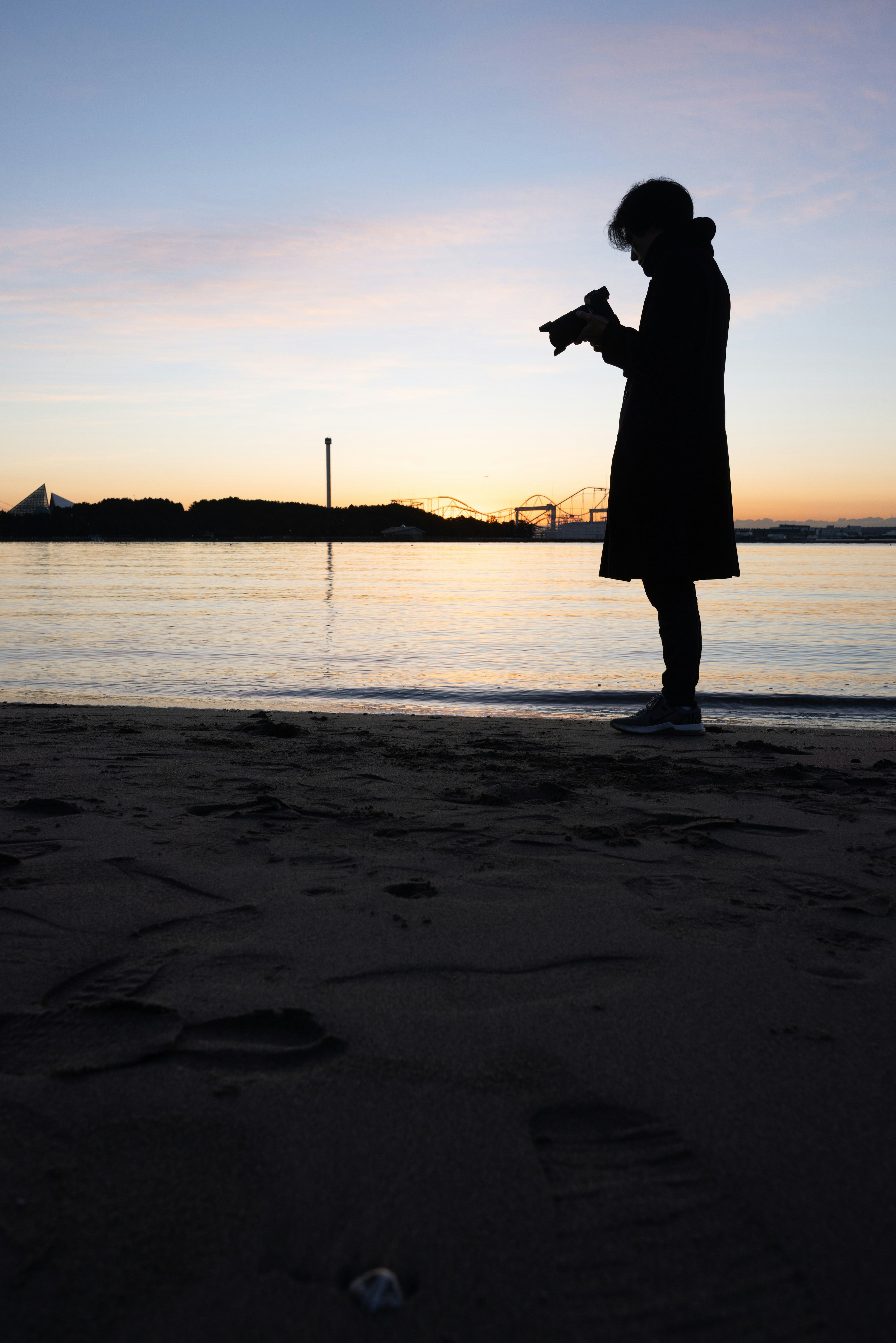 夕暮れ時のビーチでシルエットの人物がカメラを持っている