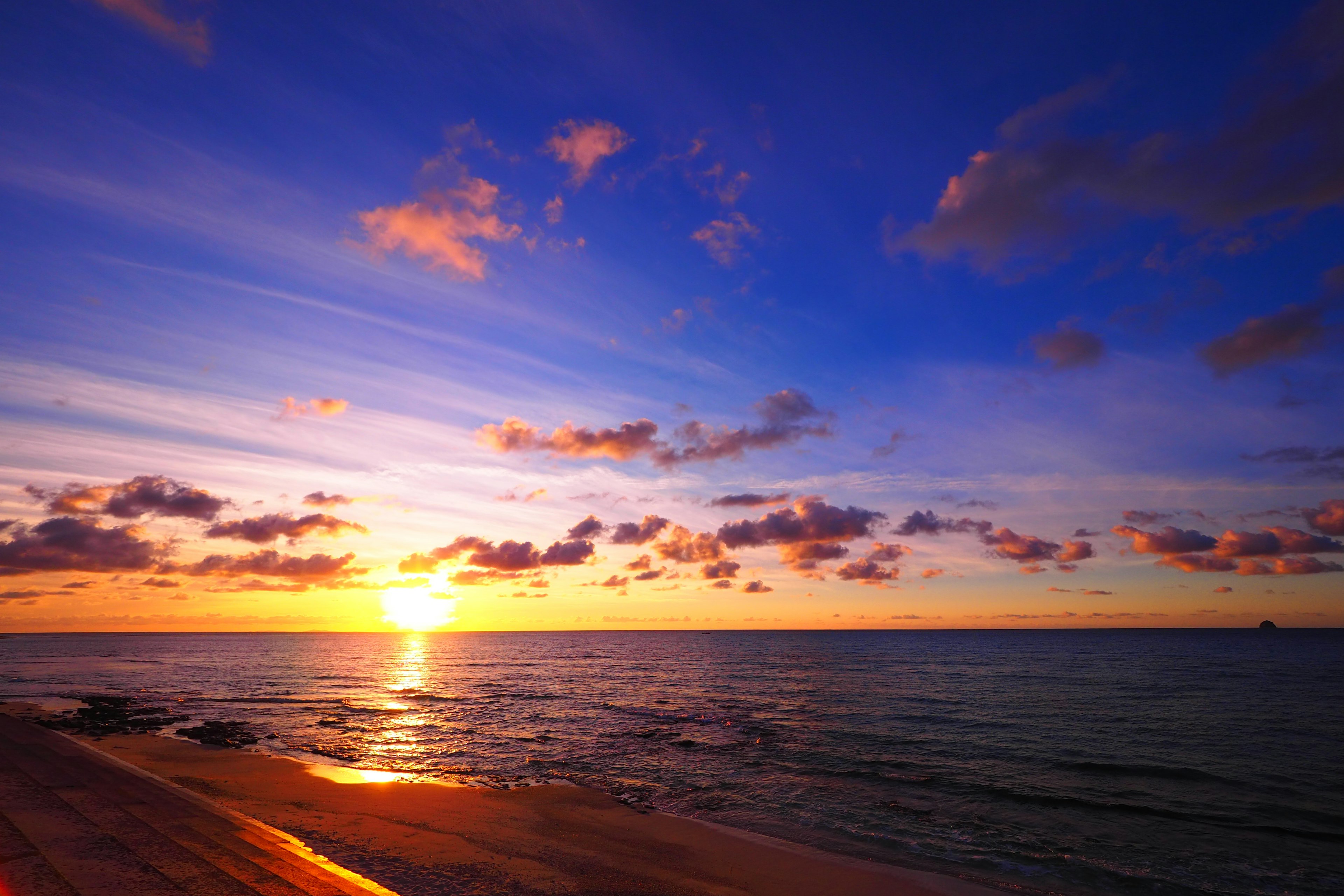 Hermoso atardecer reflejándose en el mar con un cielo azul y nubes