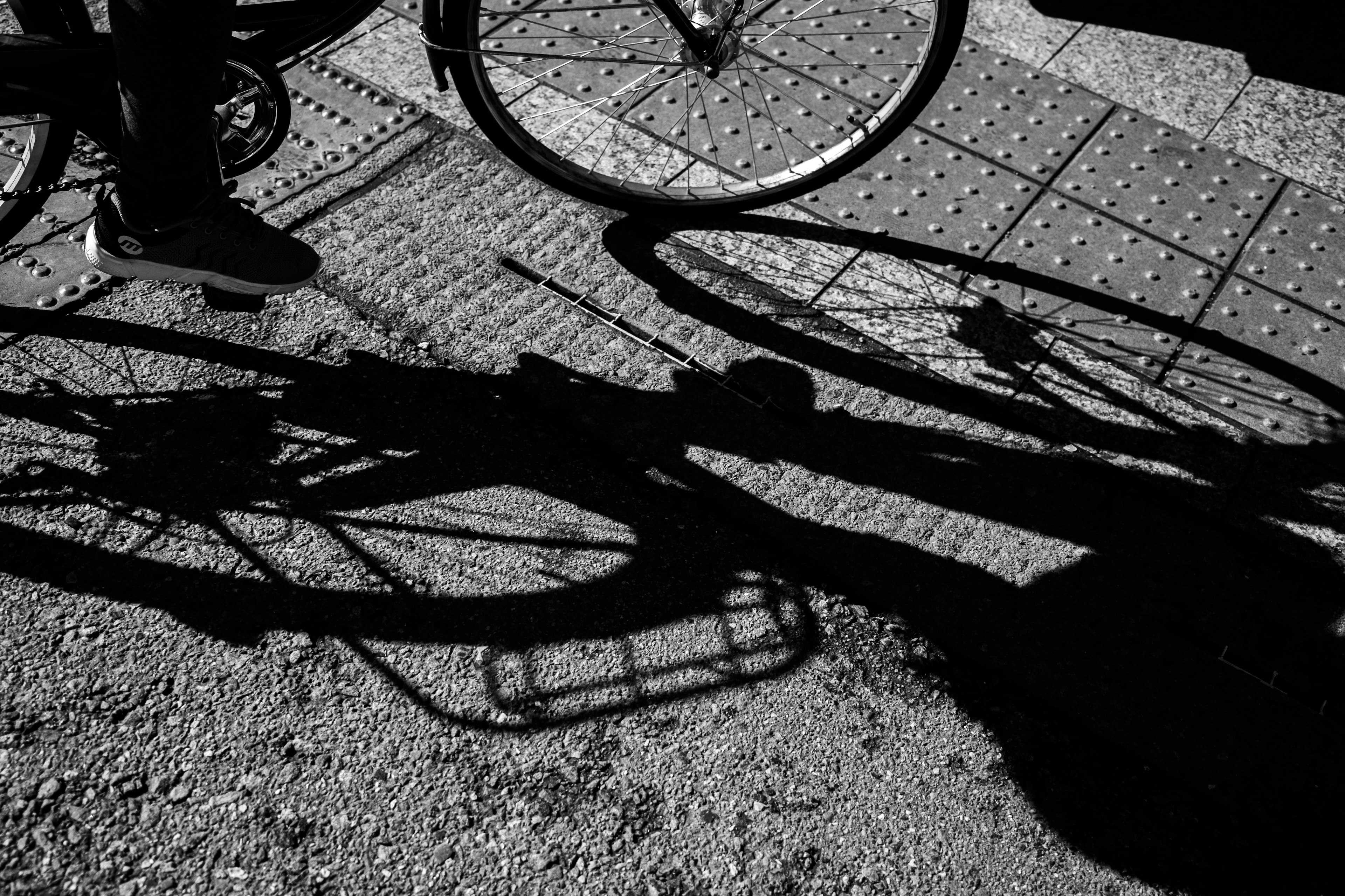 Black and white photograph of a bicycle shadow on the ground