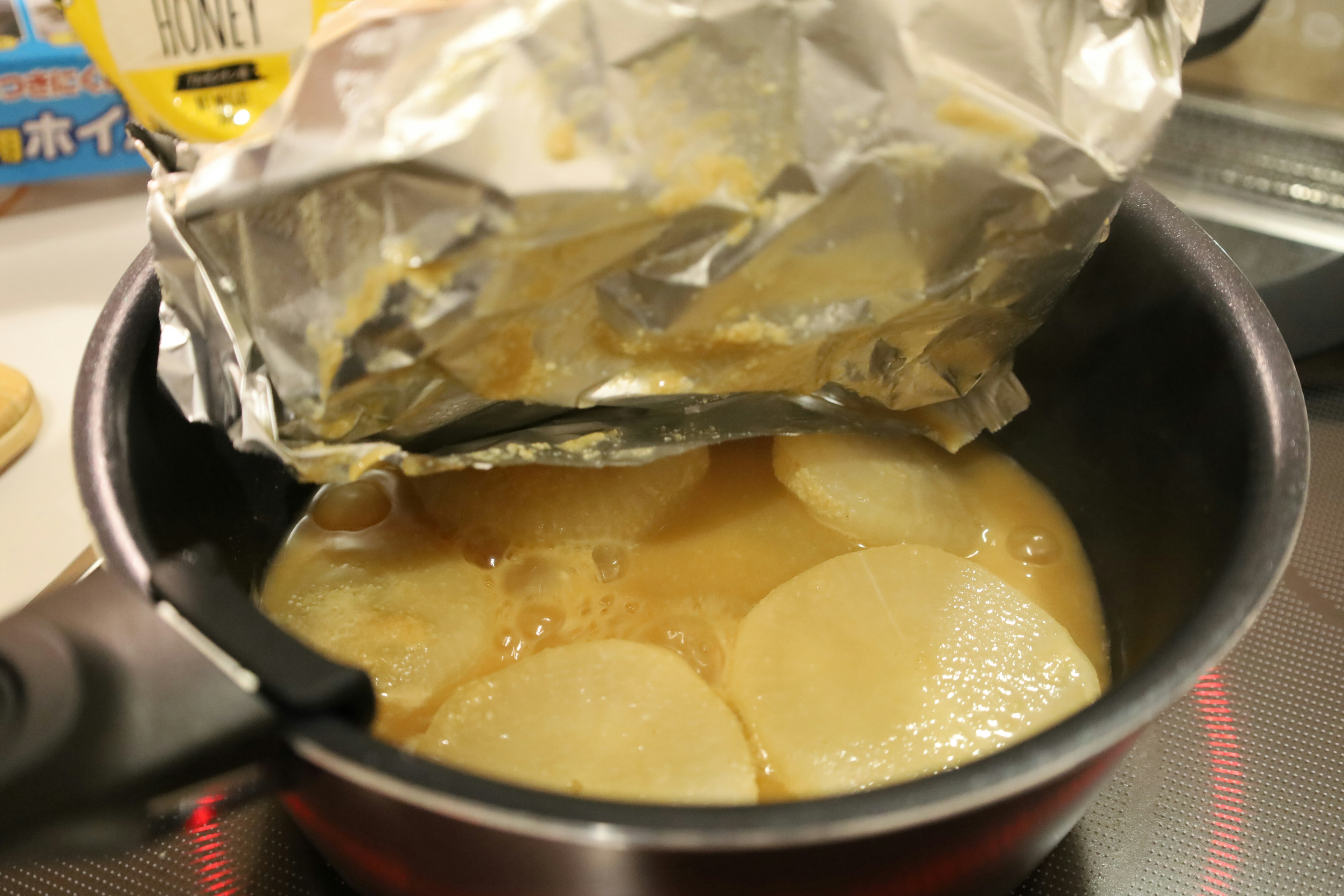 Radishes being simmered in a pot with aluminum foil covering