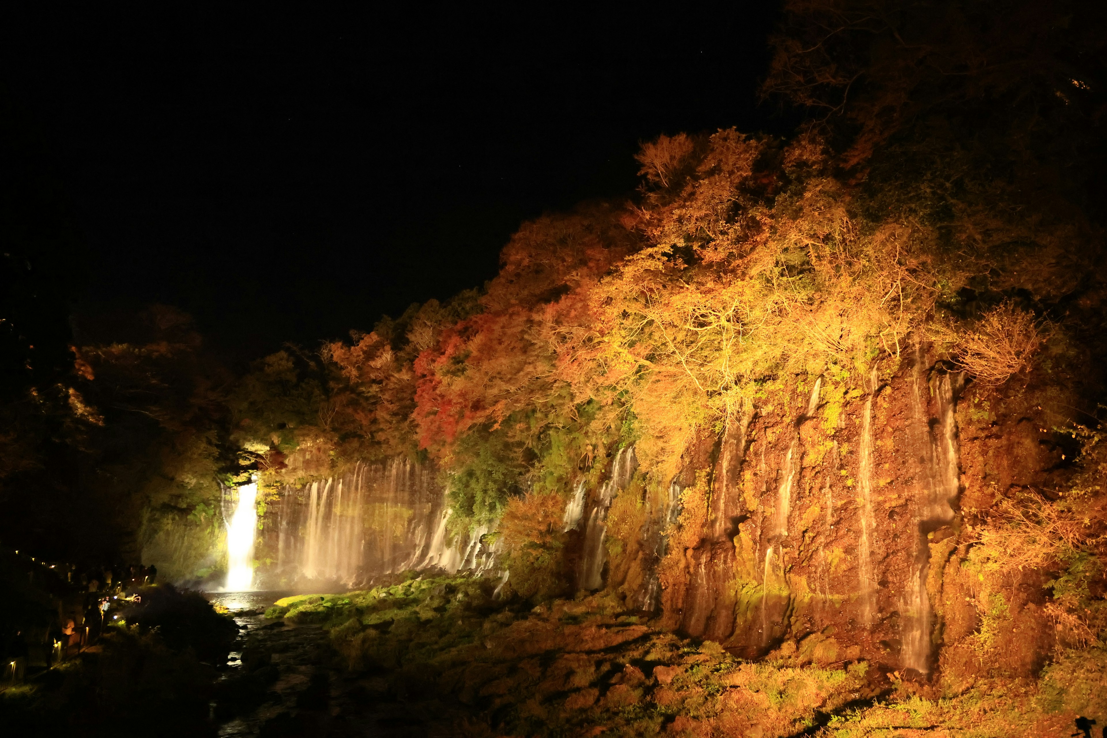 Beautiful night scene of a waterfall with autumn foliage