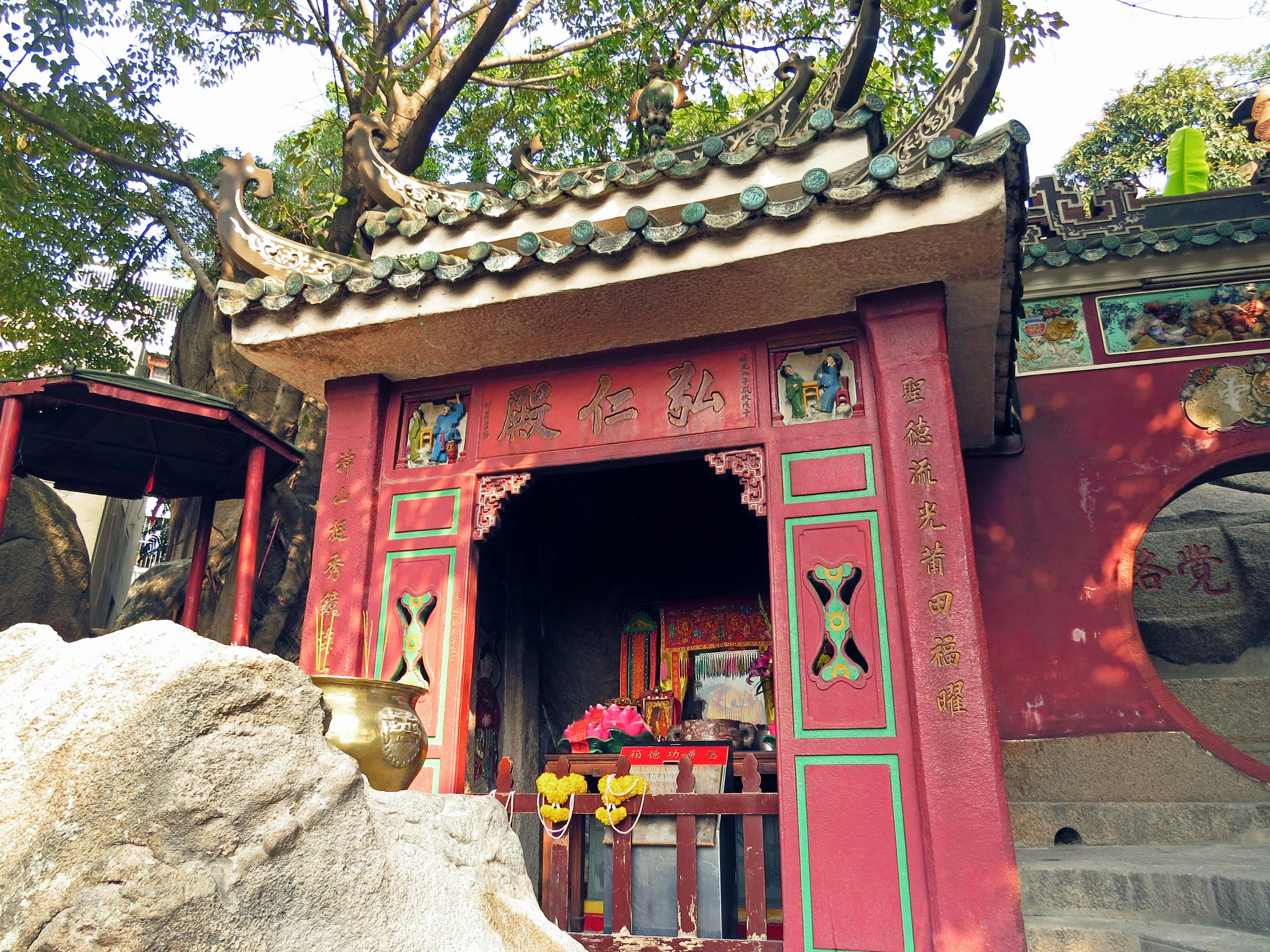 赤い壁の寺院の入り口と装飾的な屋根が特徴の風景