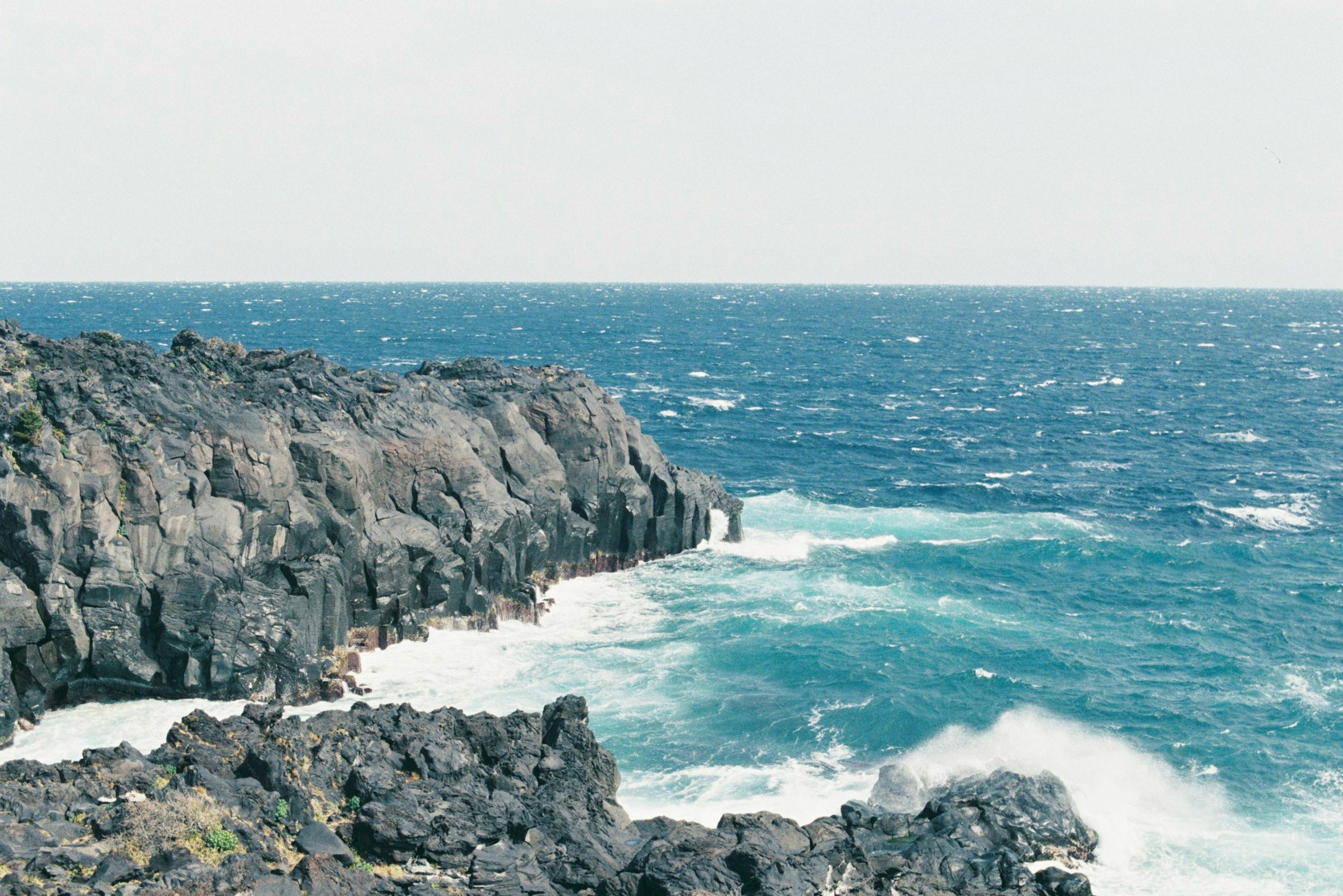 Rocky coastline with crashing waves and blue ocean