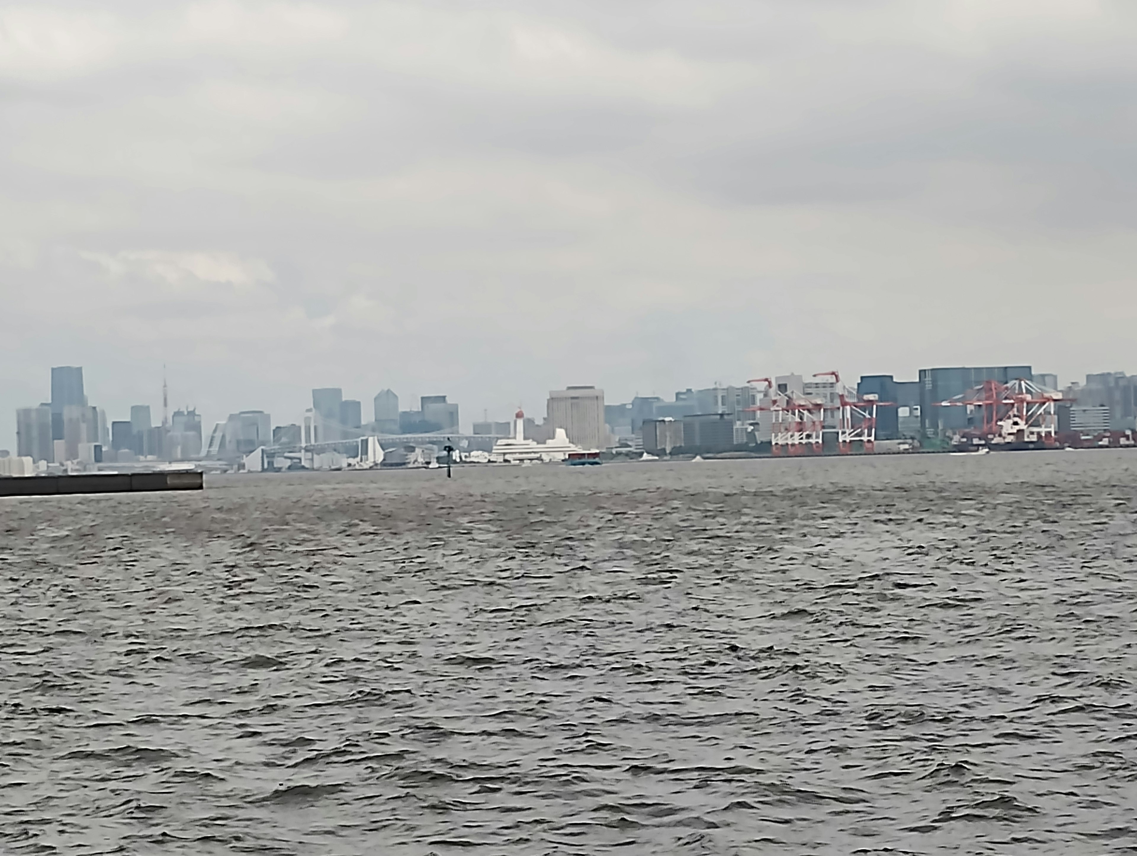 Pemandangan laut dan garis langit kota dengan langit mendung dan kapal berlabuh