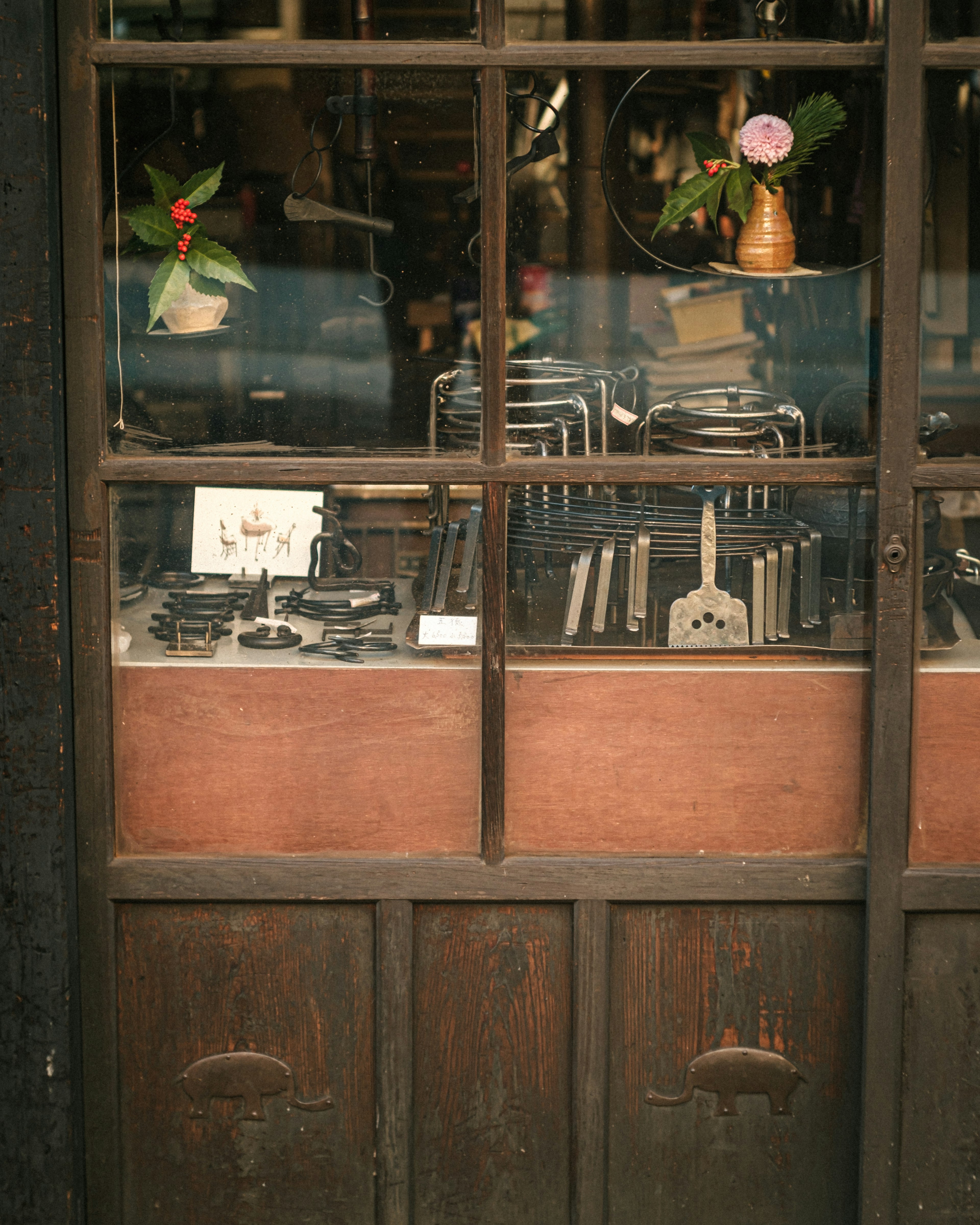 Various tools displayed in an old shop window with a floral arrangement