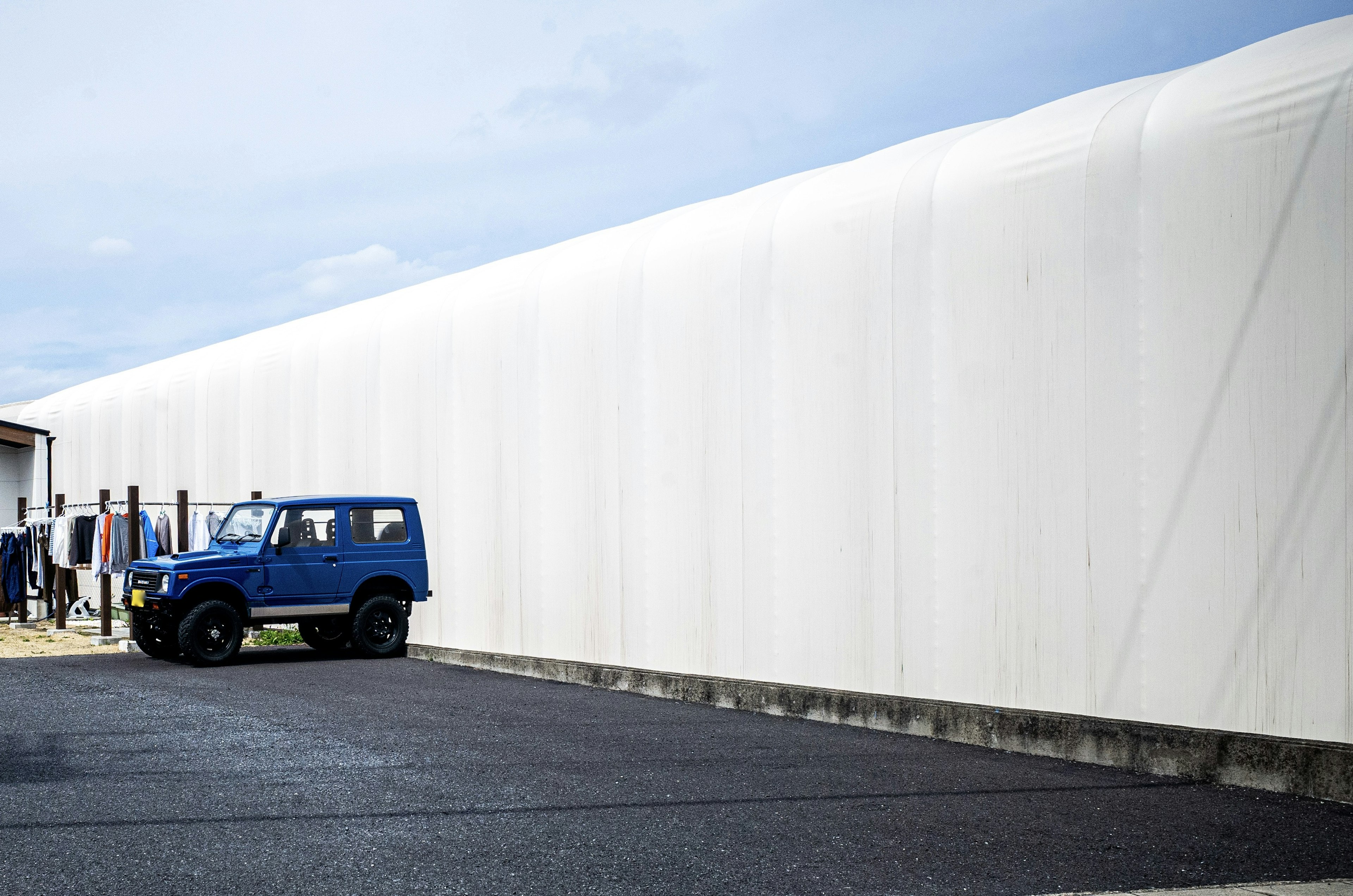 青い車と白いビニール壁がある風景