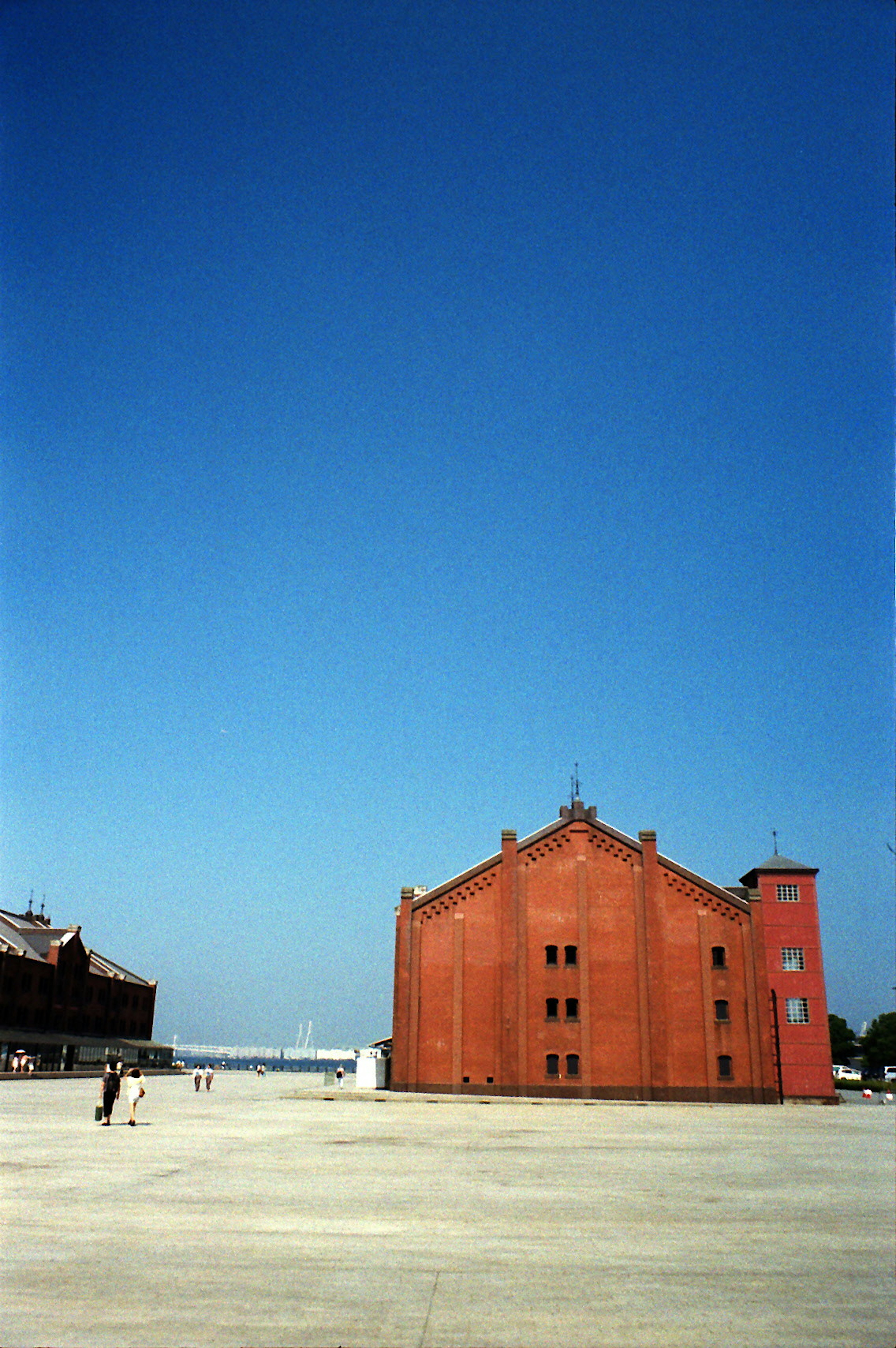 Bâtiment rouge sous un ciel bleu dégagé avec une grande place