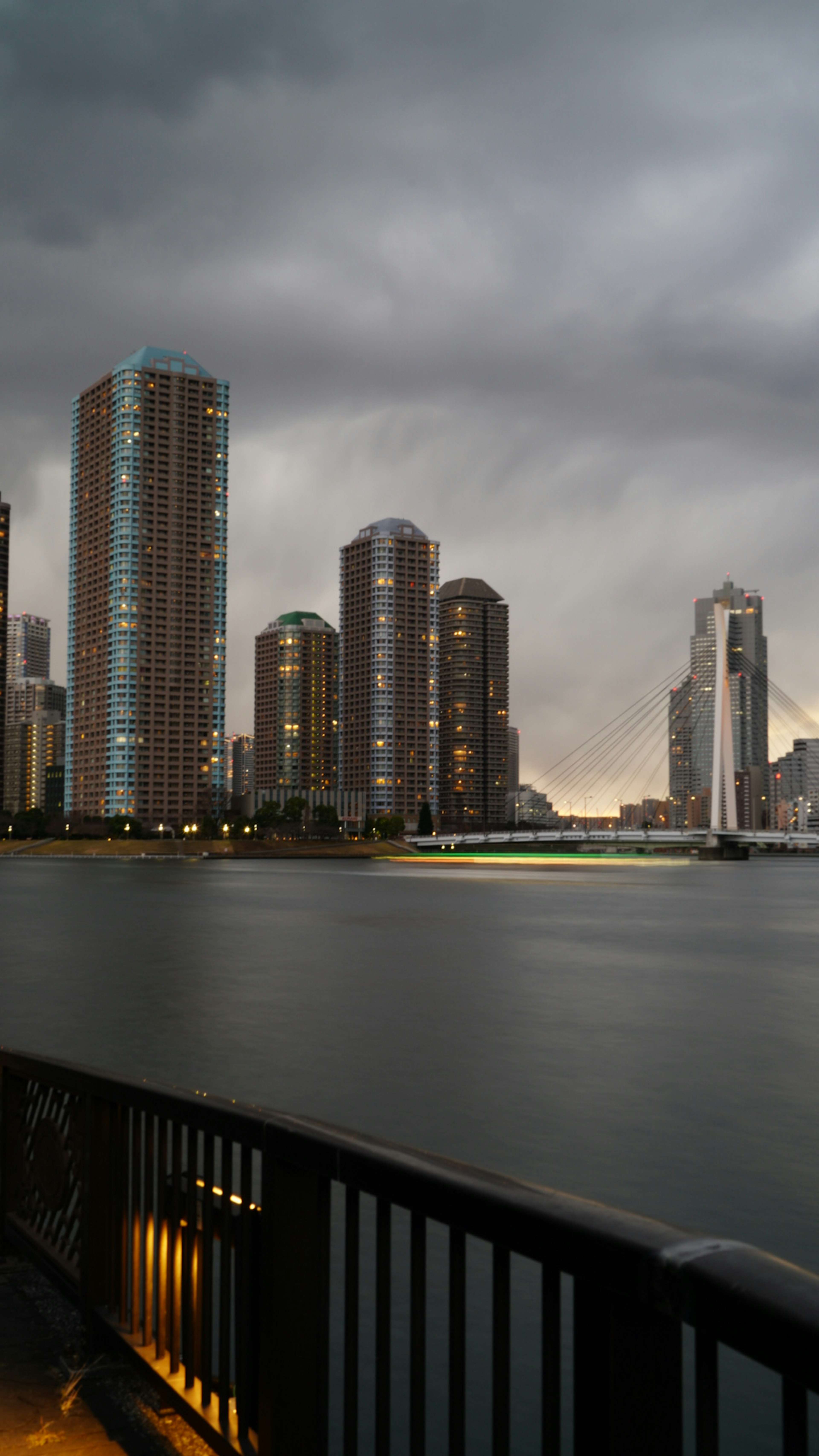 Paisaje urbano bajo nubes oscuras con rascacielos y una superficie de agua tranquila