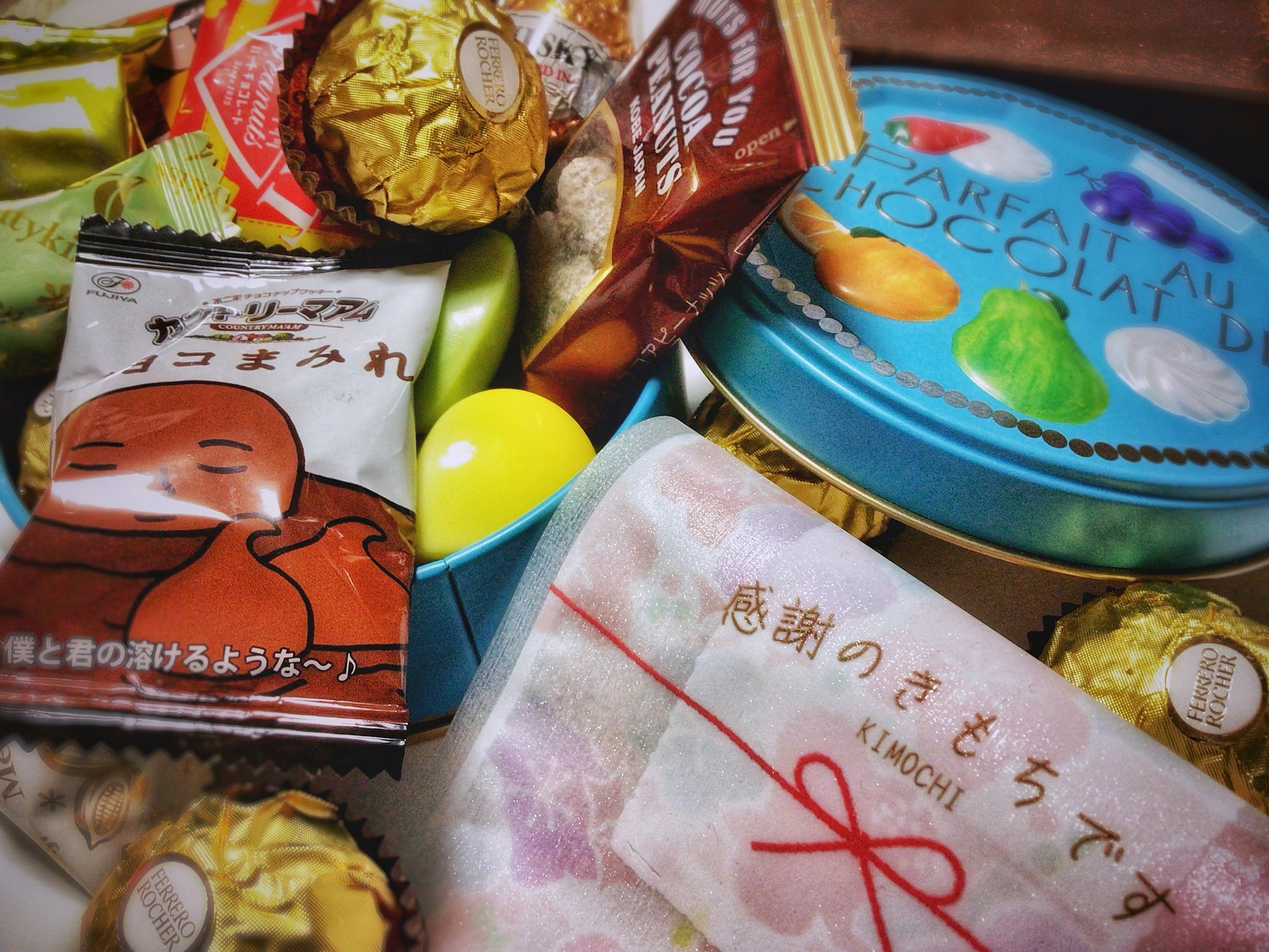 A colorful assortment of candies and snacks in a decorative tin and wrapped gift