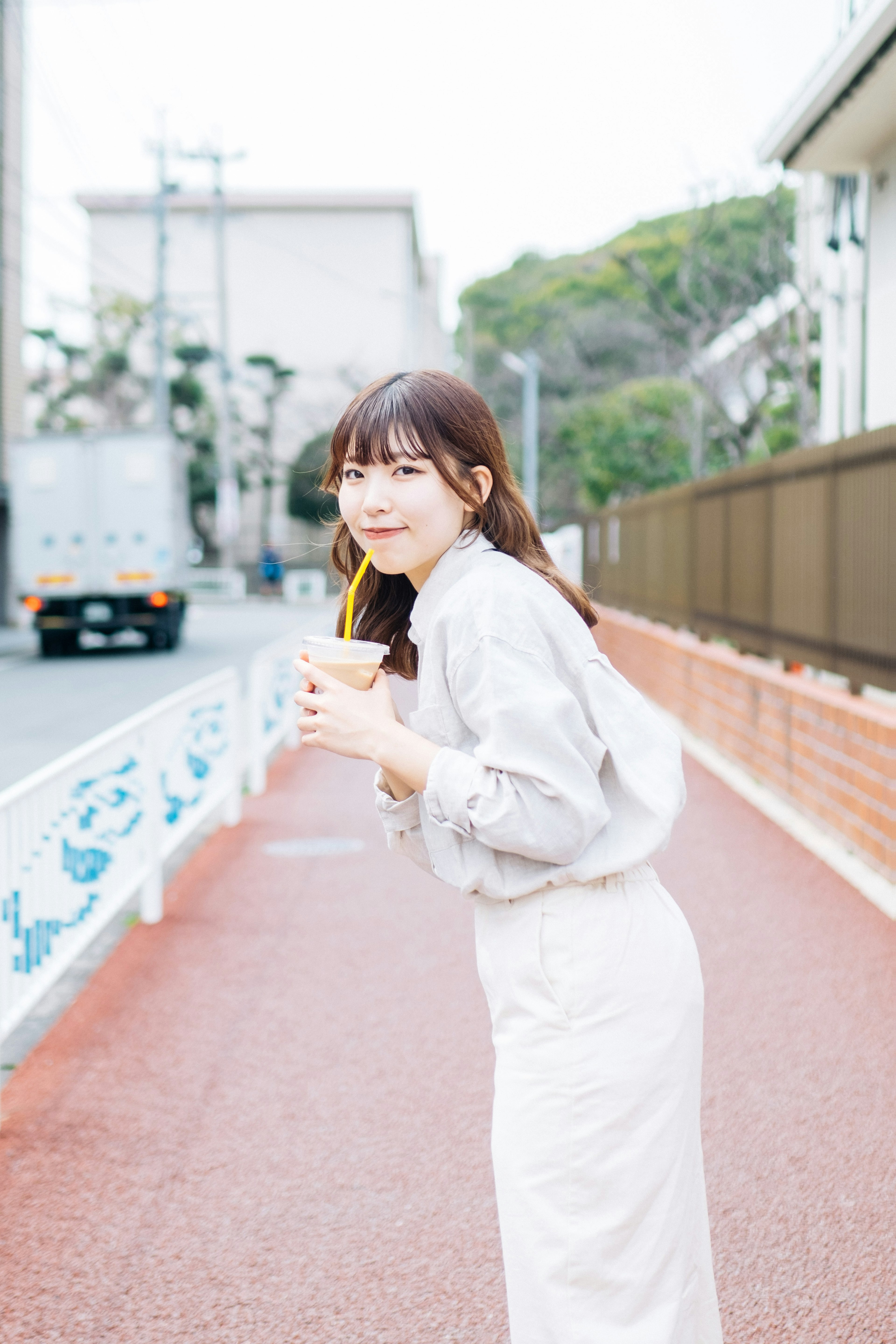 Young woman holding a drink standing on the street