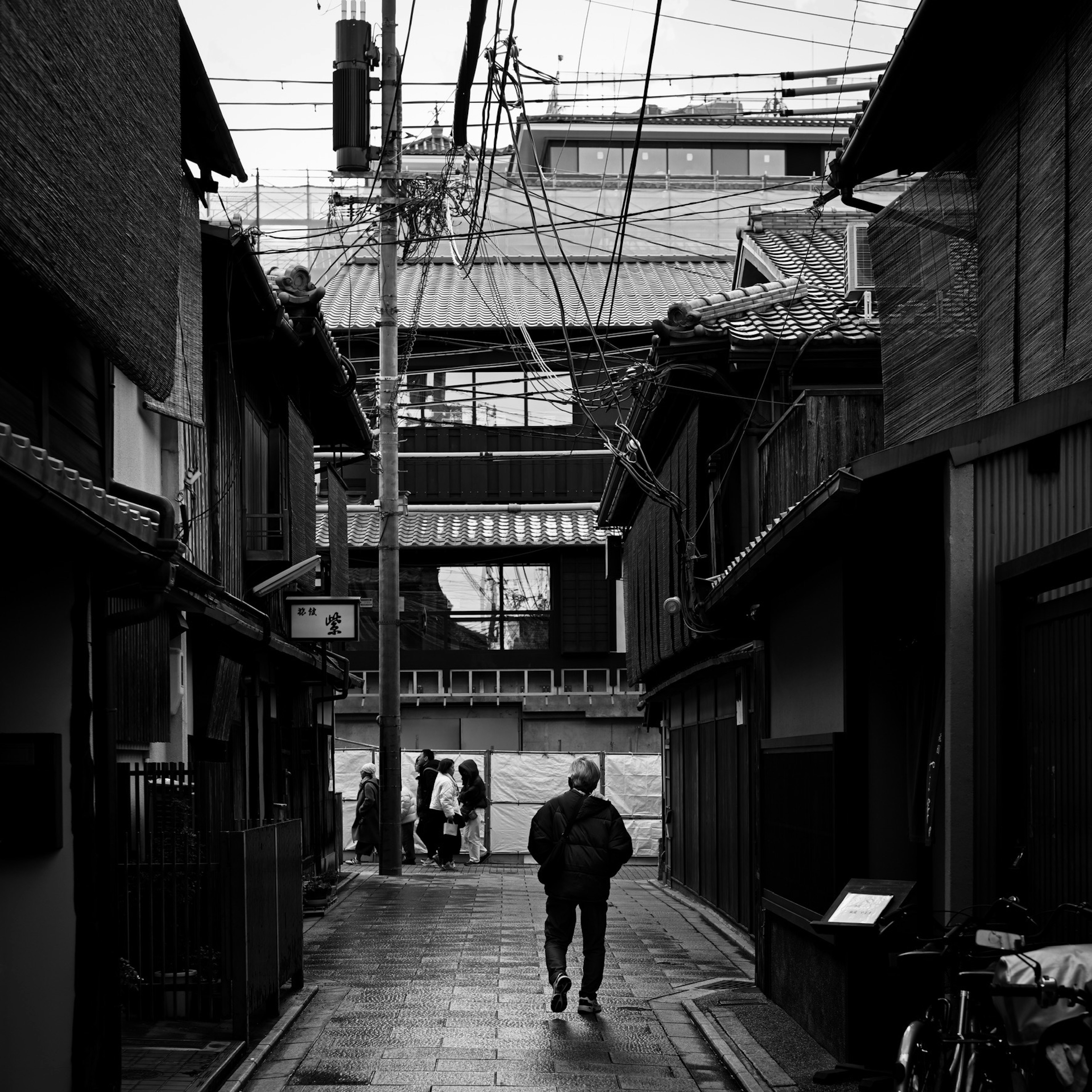 Eine Person geht durch eine ruhige japanische Gasse mit traditionellen Häusern