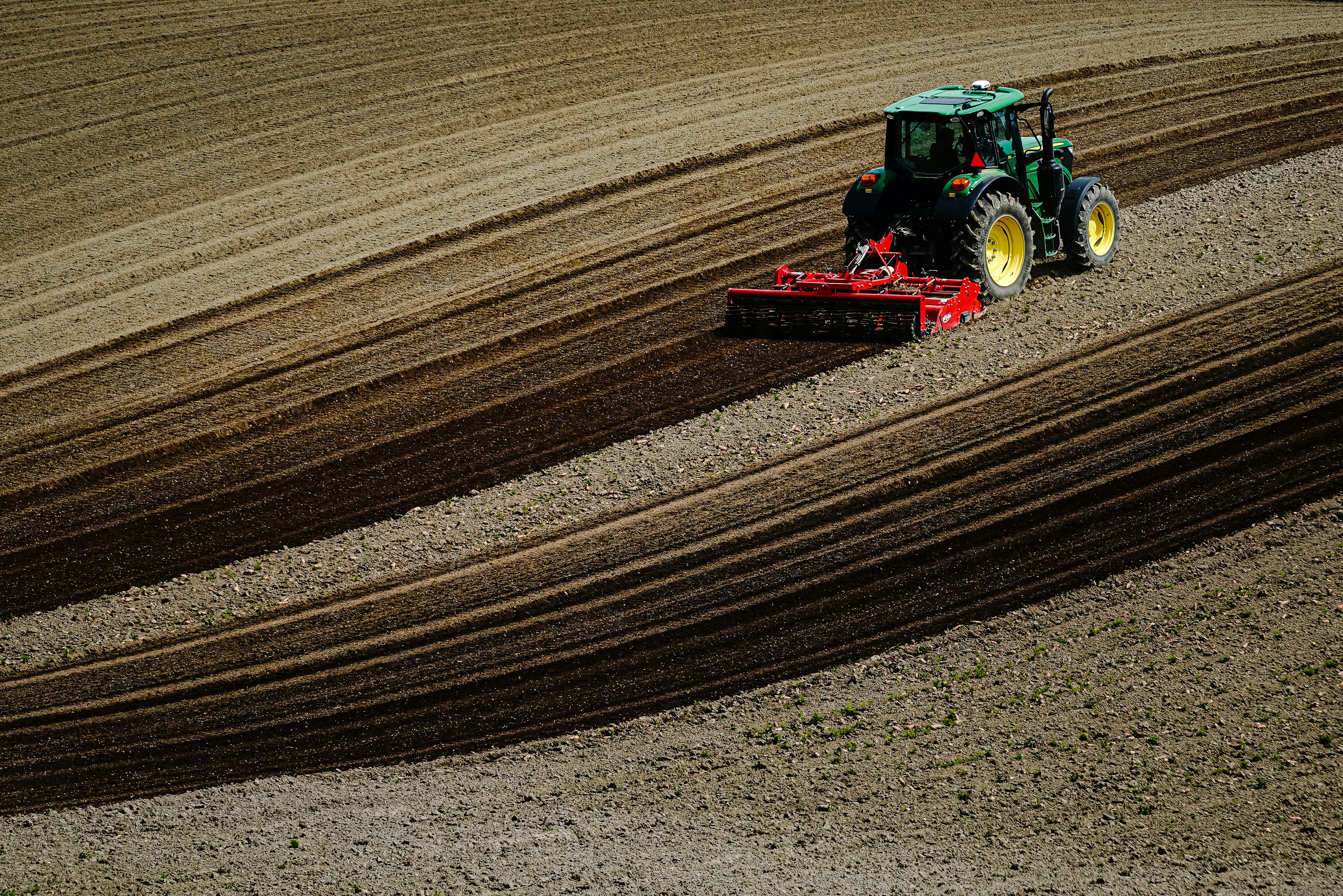 Un trattore che ara un campo con motivi di suolo distintivi