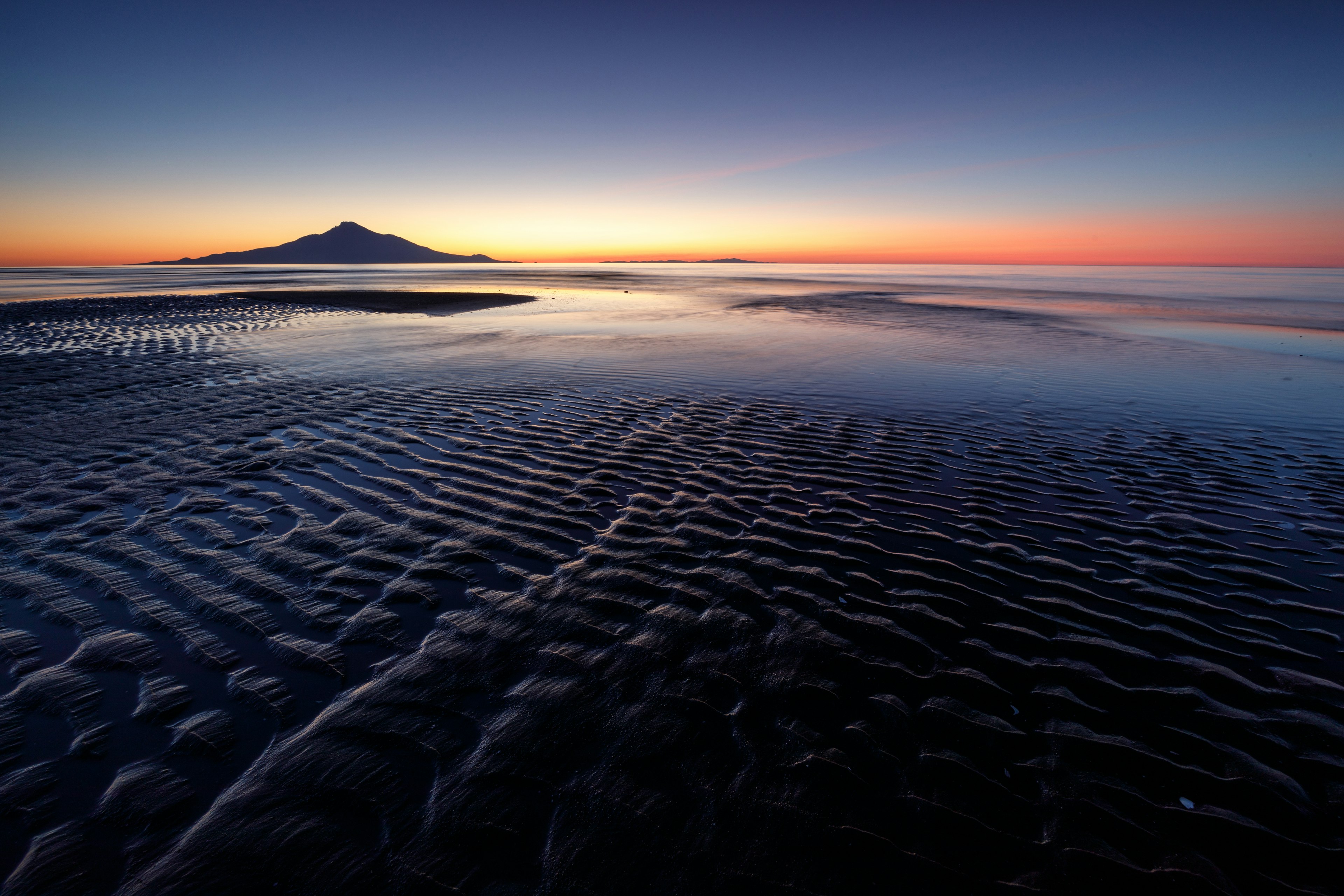 美しい夕焼けの海岸線と穏やかな波紋が広がる海の風景