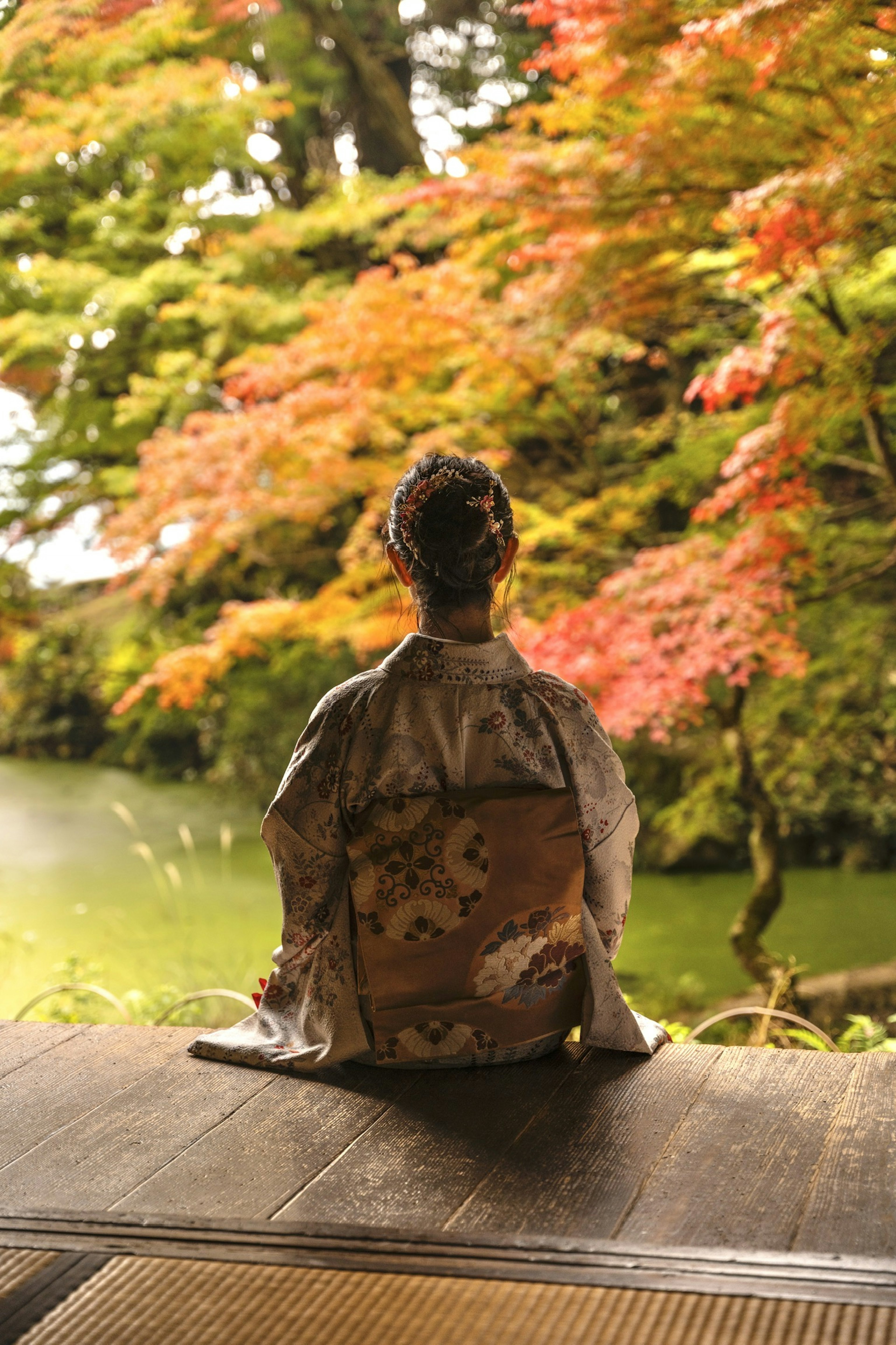 一位穿著和服的女性靜靜坐在秋天的樹葉中