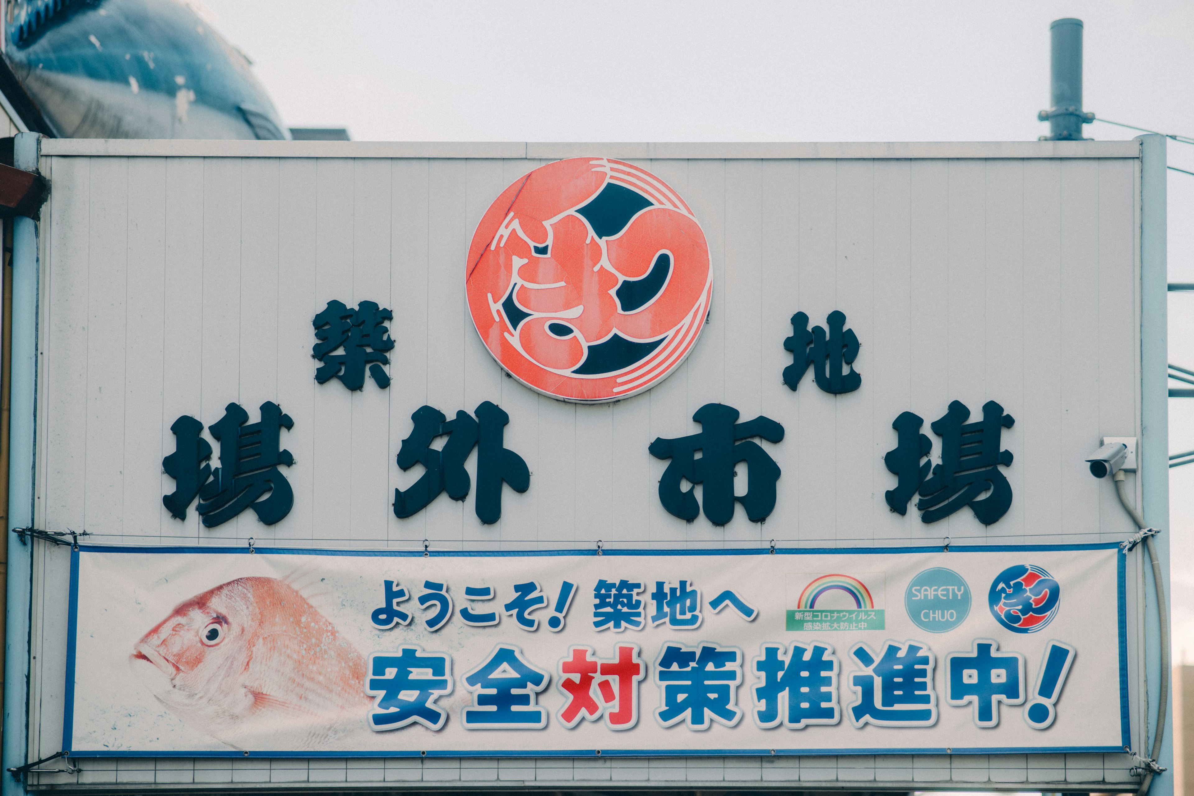 Panneau d'un marché aux fruits de mer avec une illustration de crevette et un texte d'accueil en japonais