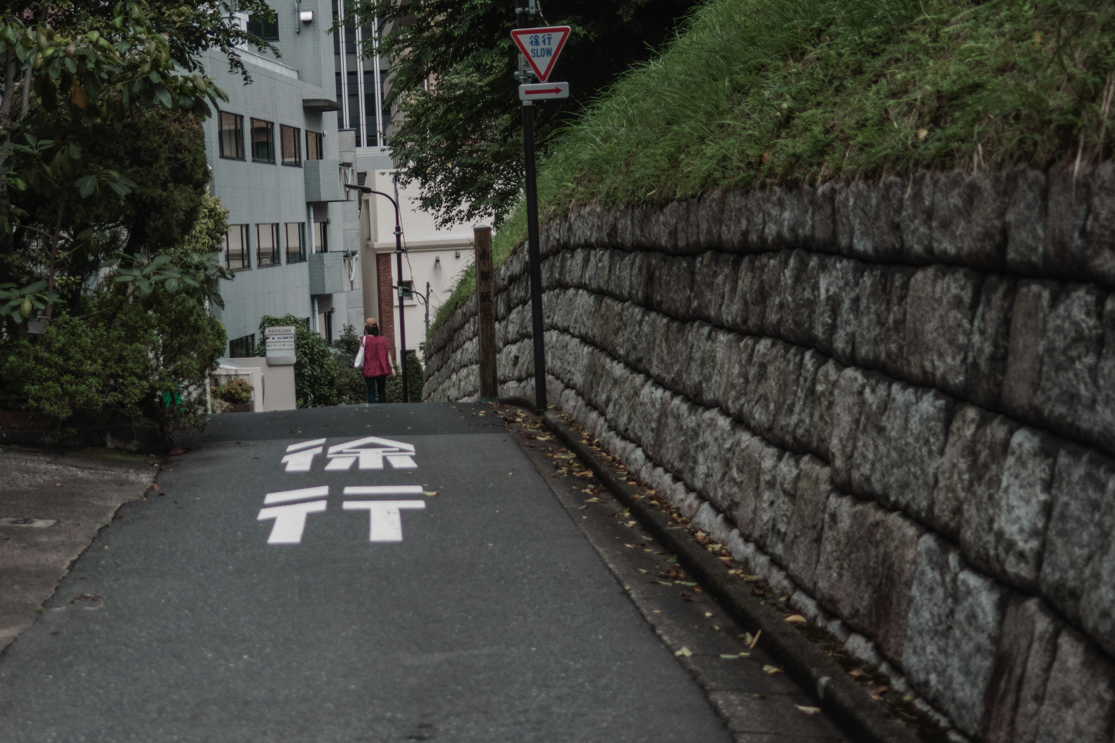 狭い道に沿った石の壁と白い文字の標識