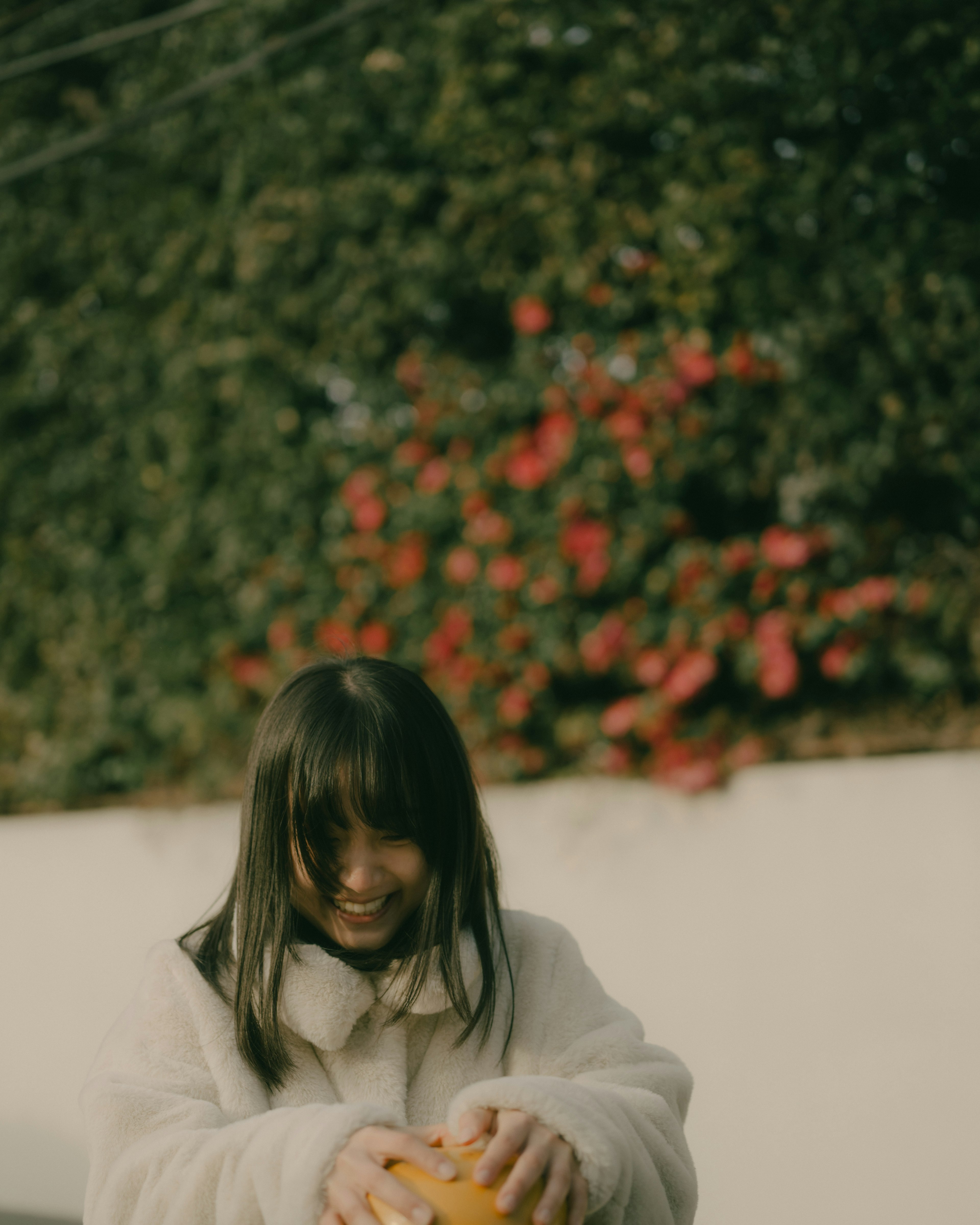 Ragazza sorridente che tiene un'arancia con fiori colorati sullo sfondo