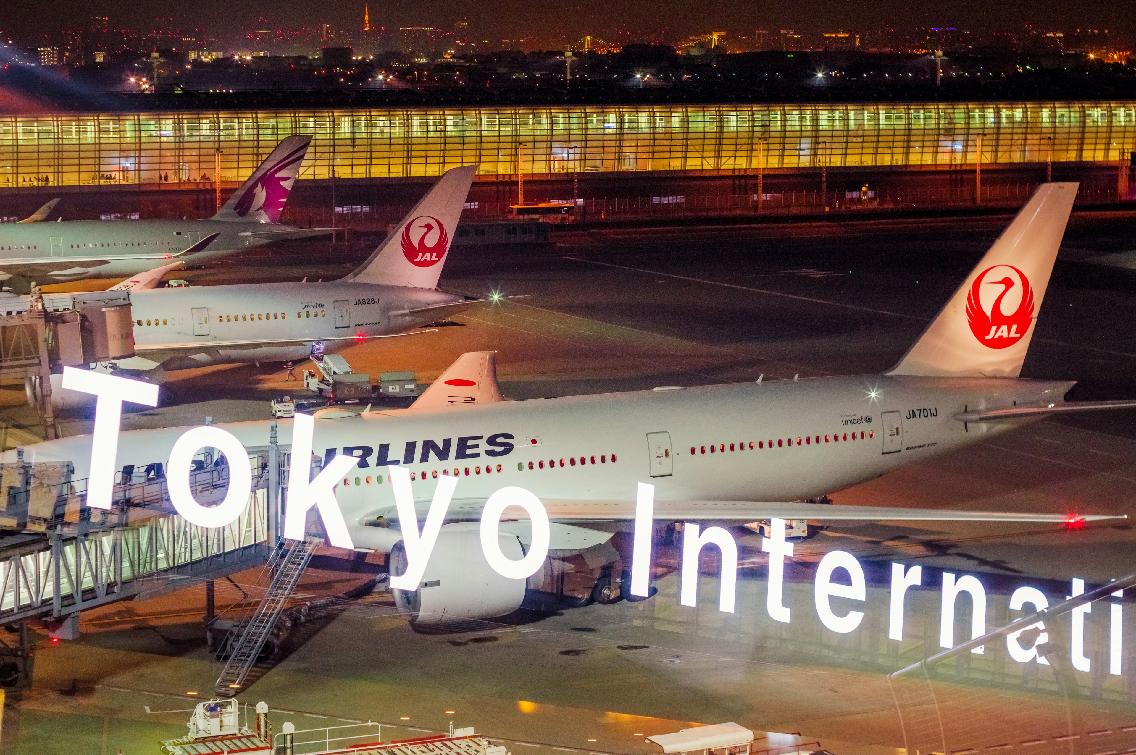 Flugzeuge am internationalen Flughafen Tokio mit beleuchteter Beschilderung in der Nacht