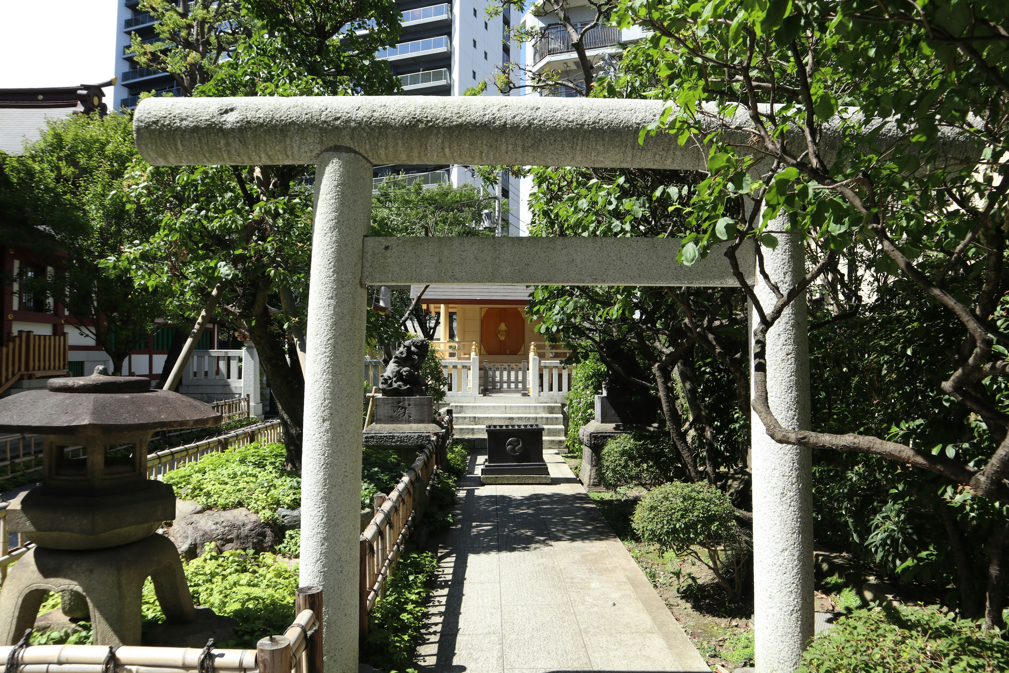 Giardino giapponese con un torii e una lanterna di pietra circondati da vegetazione