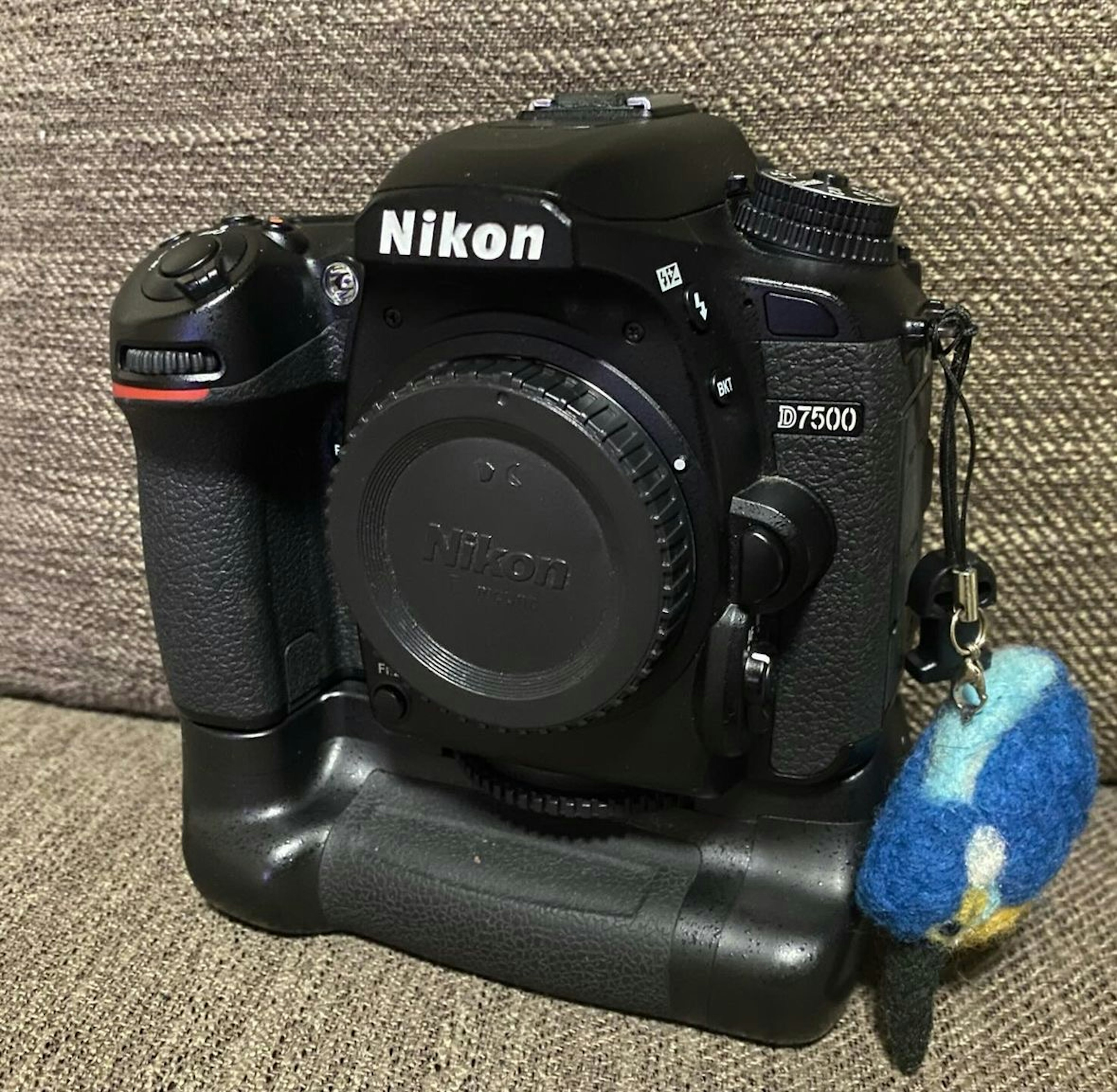 Nikon D7500 camera with colorful keychain attached to battery grip