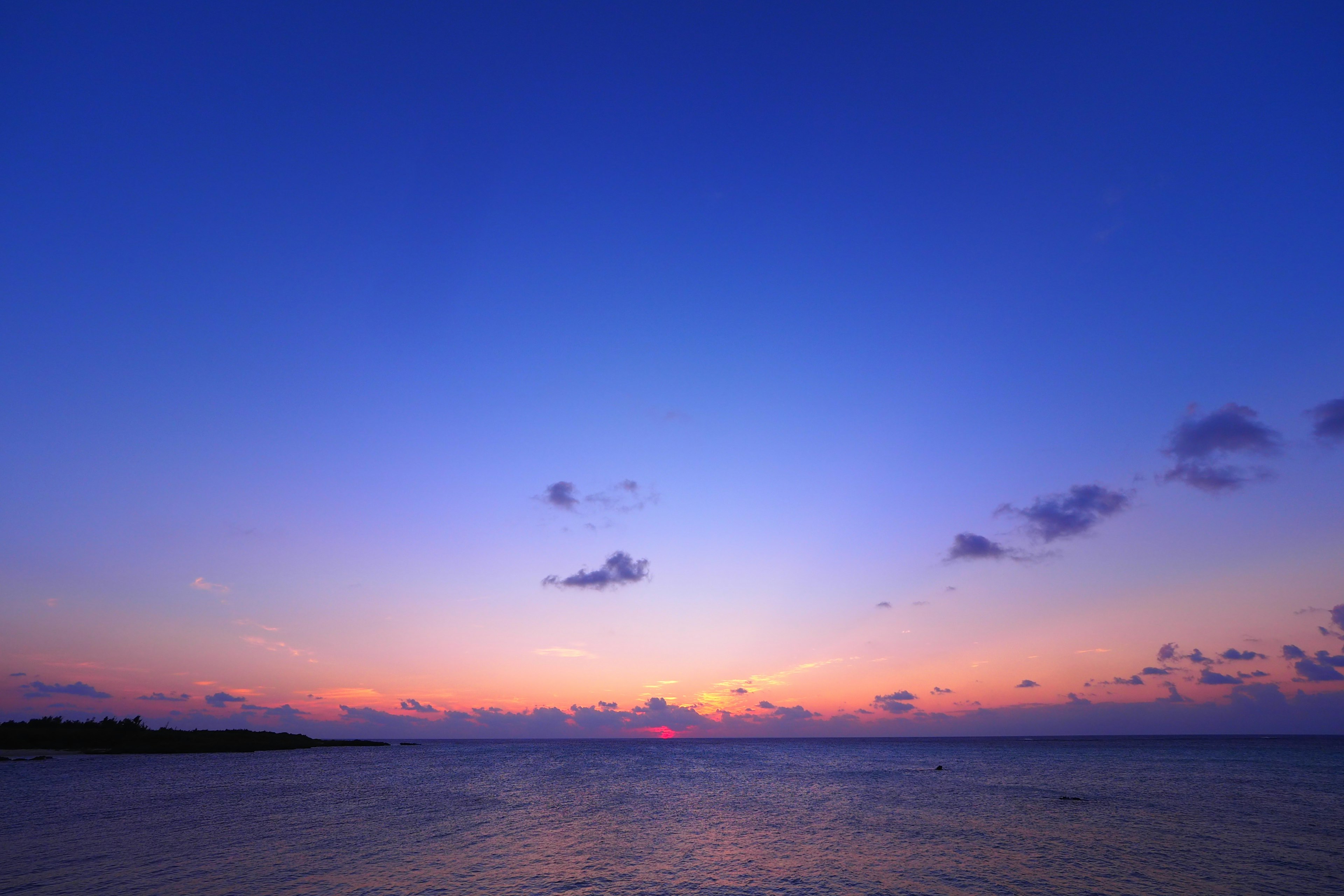 Ciel bleu avec coucher de soleil orange se reflétant sur la mer