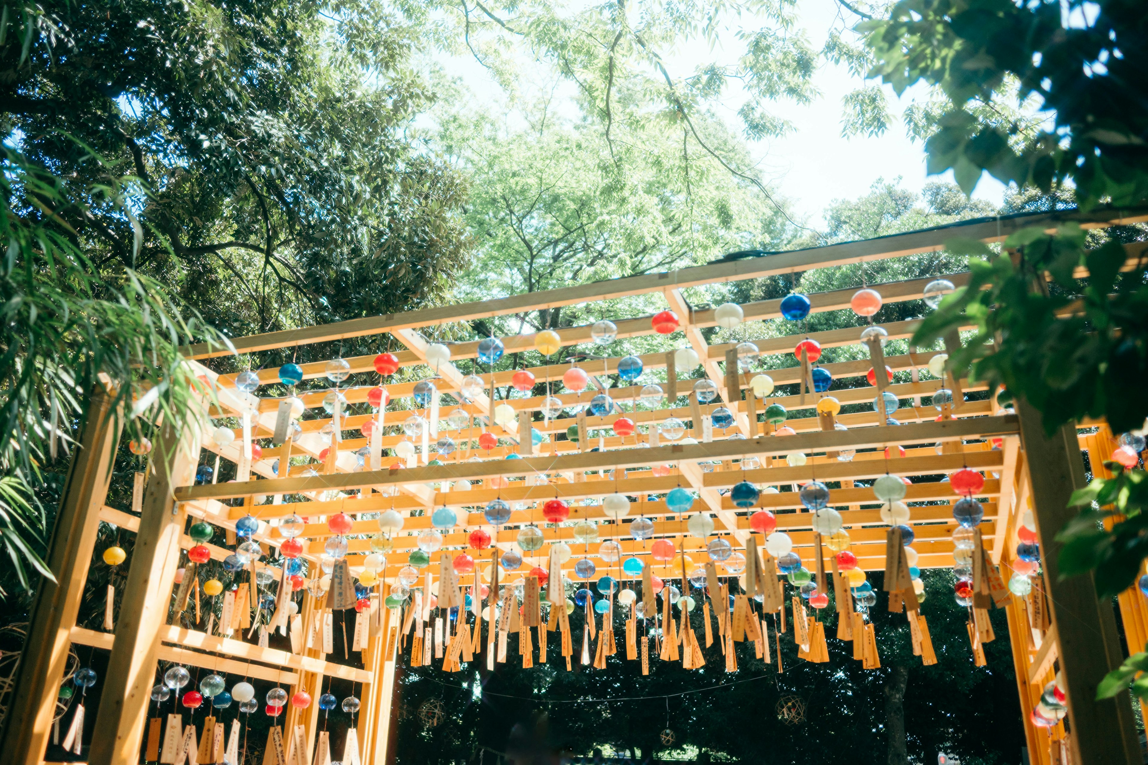 Wooden structure with colorful wind chimes hanging under a blue sky