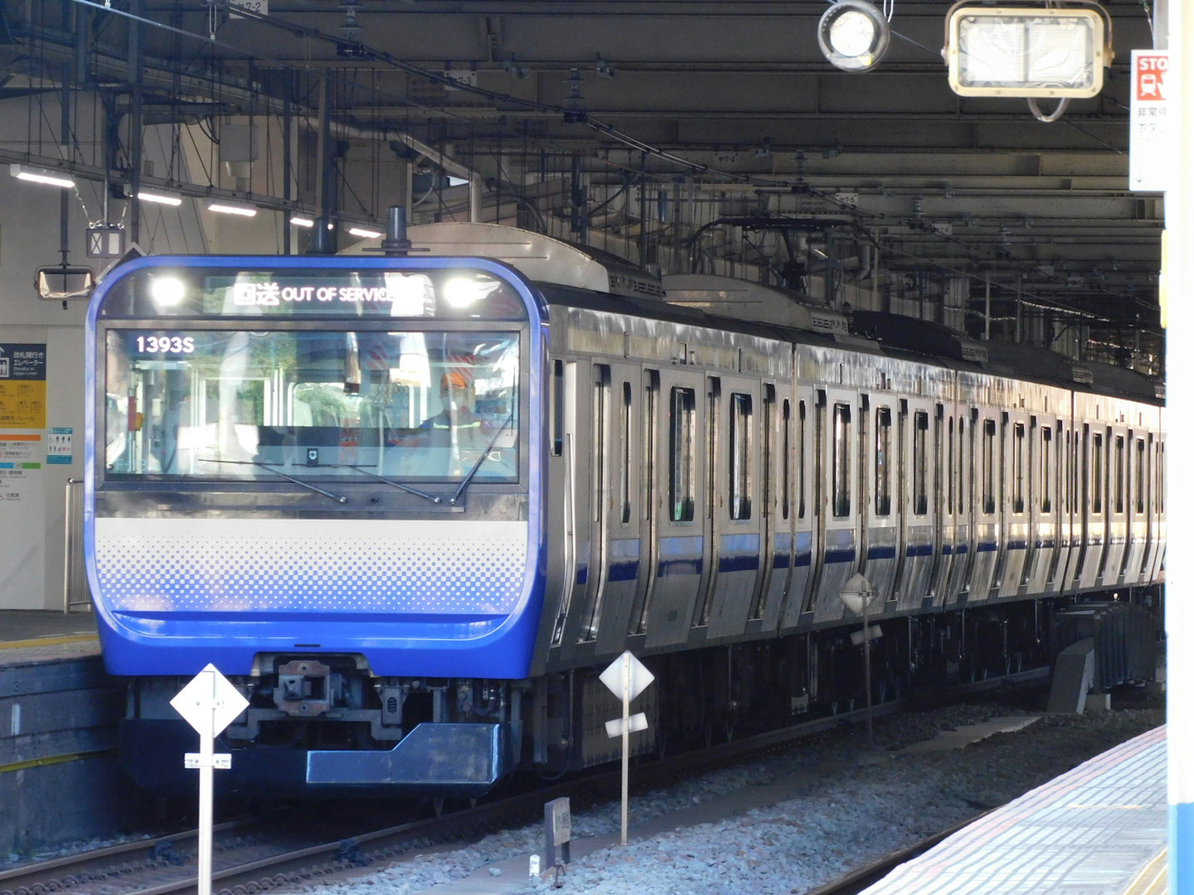 A blue-bodied train is stopped at a station