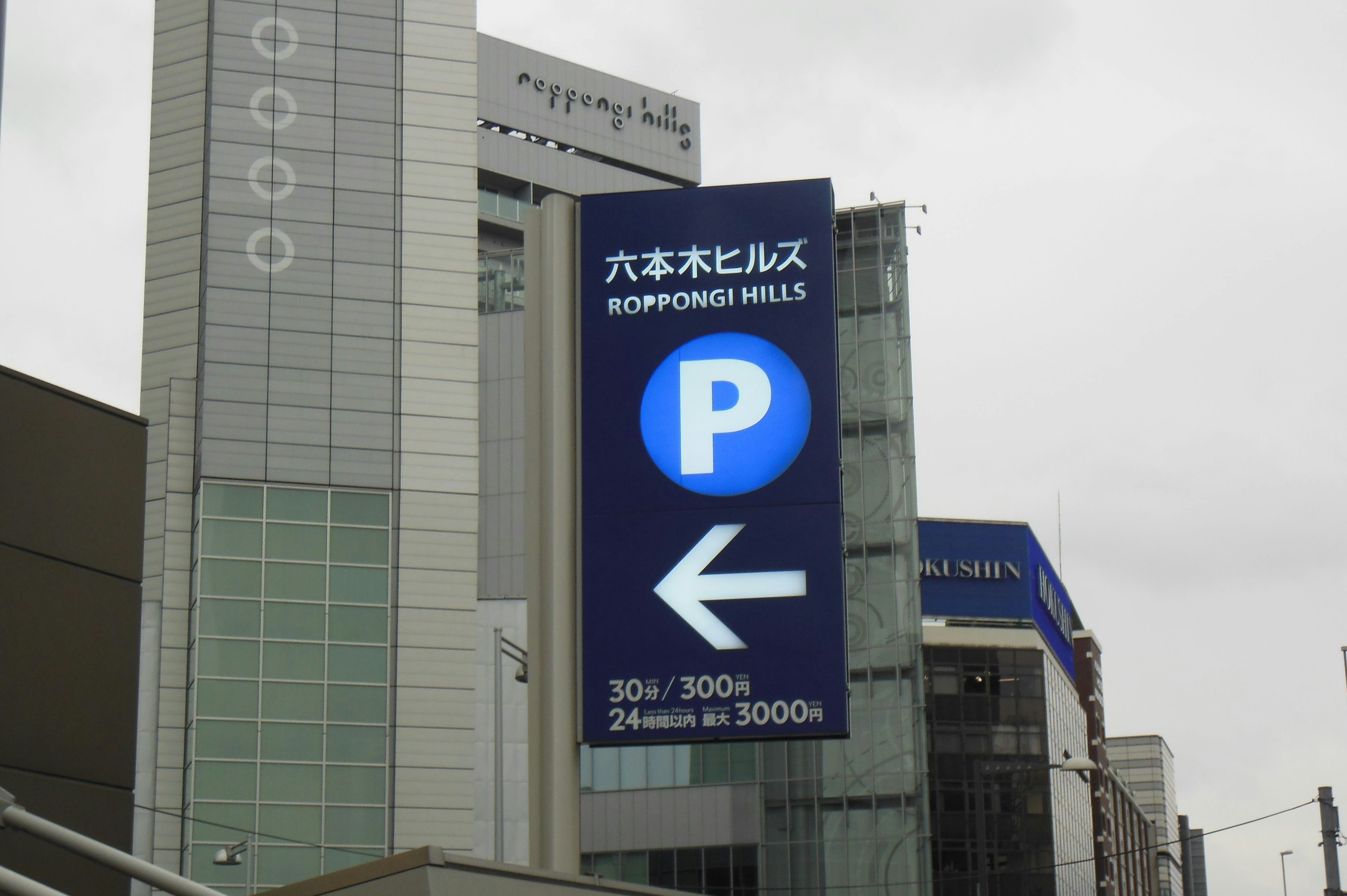 Segnale di parcheggio per Roppongi Hills con sfondo blu e freccia a sinistra