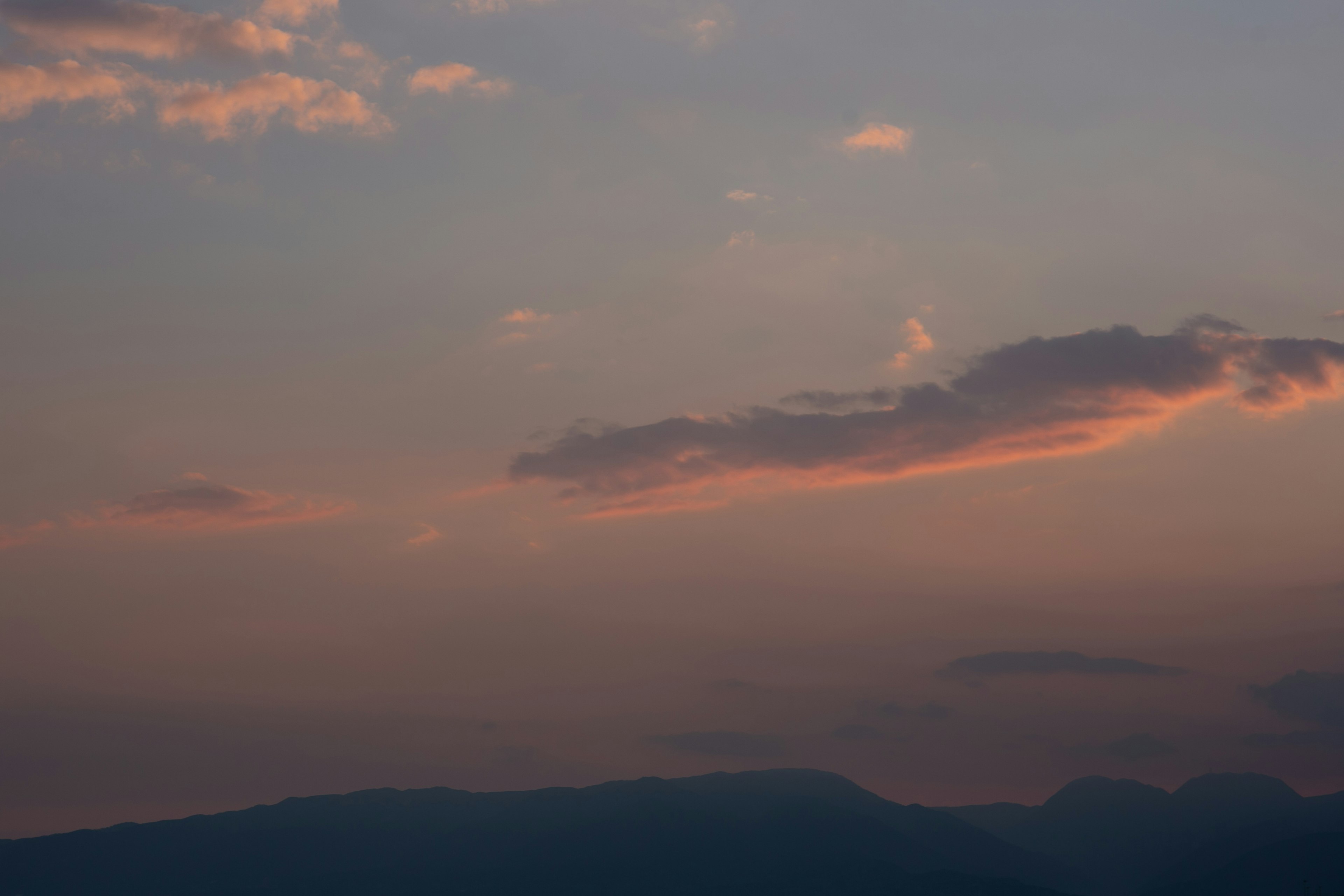 山のシルエットと夕焼けの空に浮かぶ雲