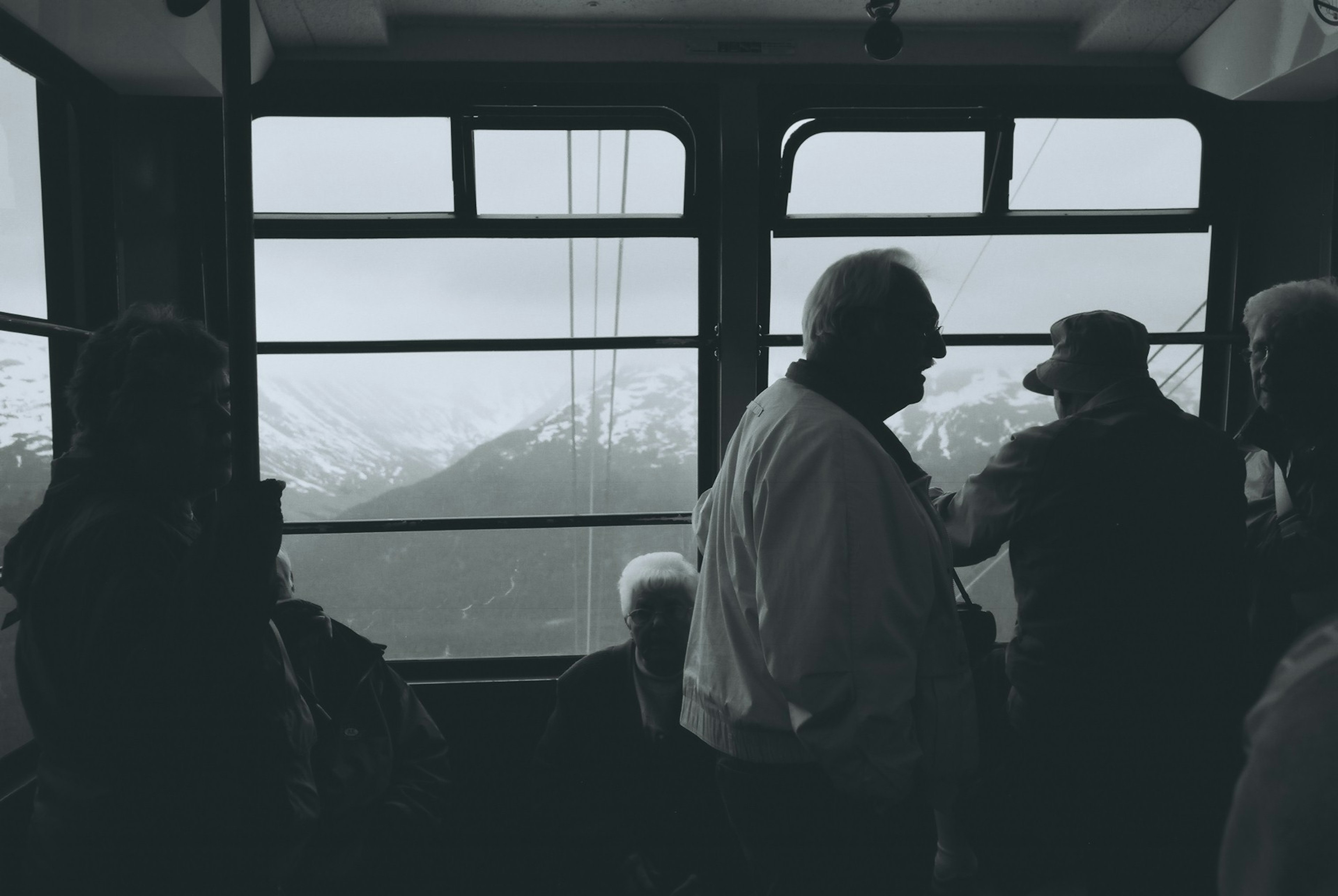 People inside a cable car with a mountain view in the background