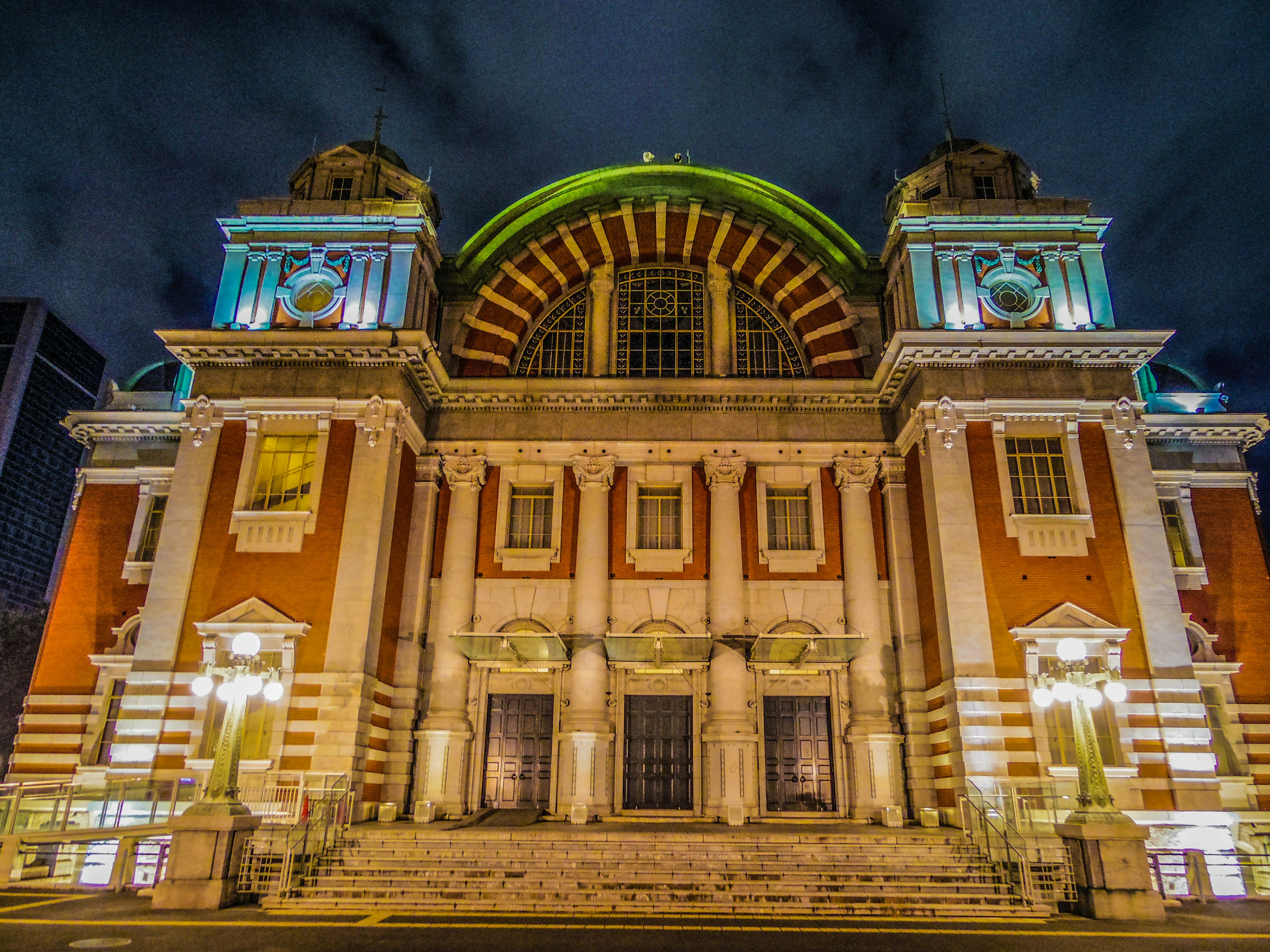 Vista frontale di un edificio stupendo di notte con un tetto ad arco e una facciata decorativa