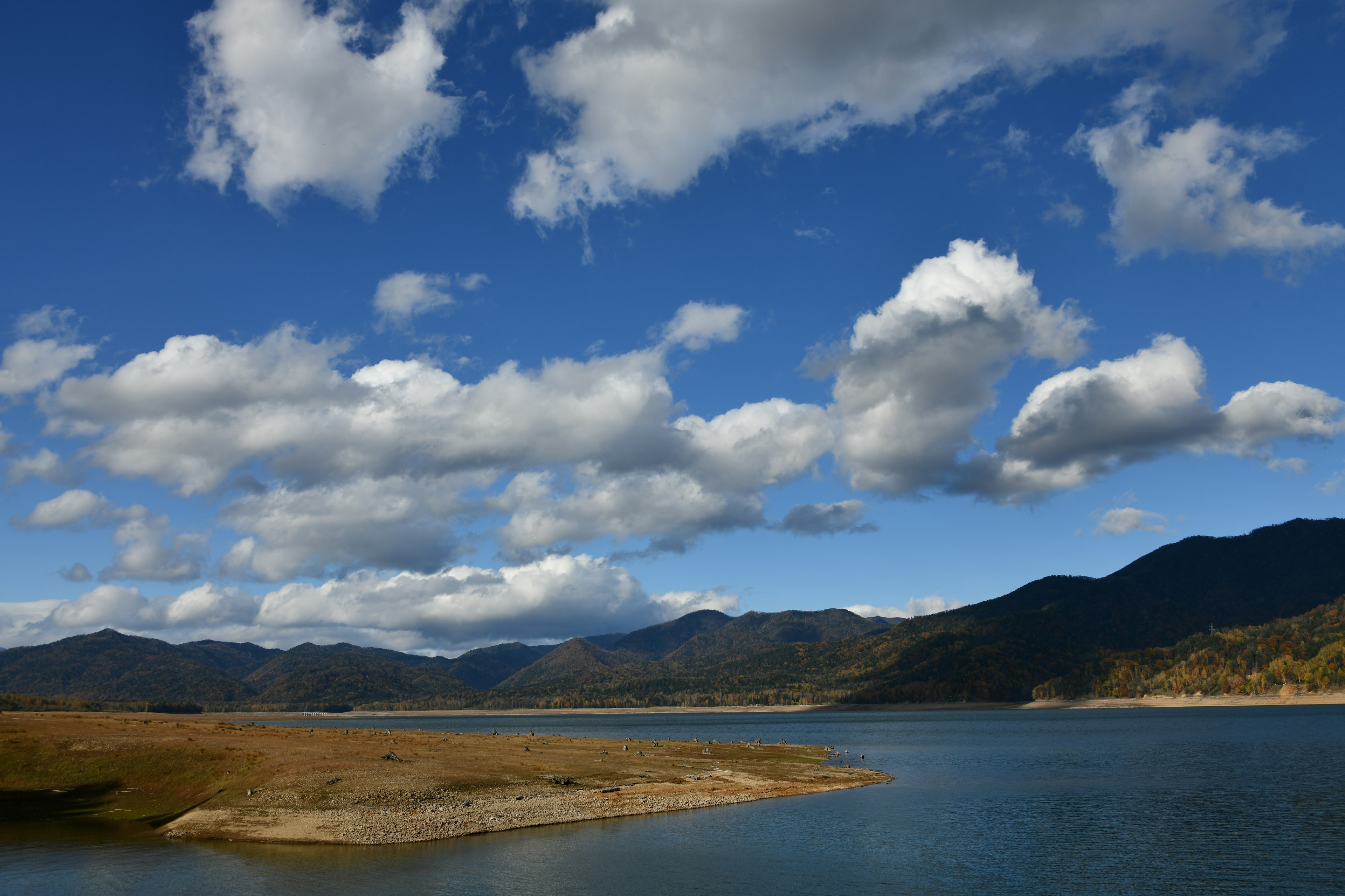 青い湖と山々の風景に広がる白い雲