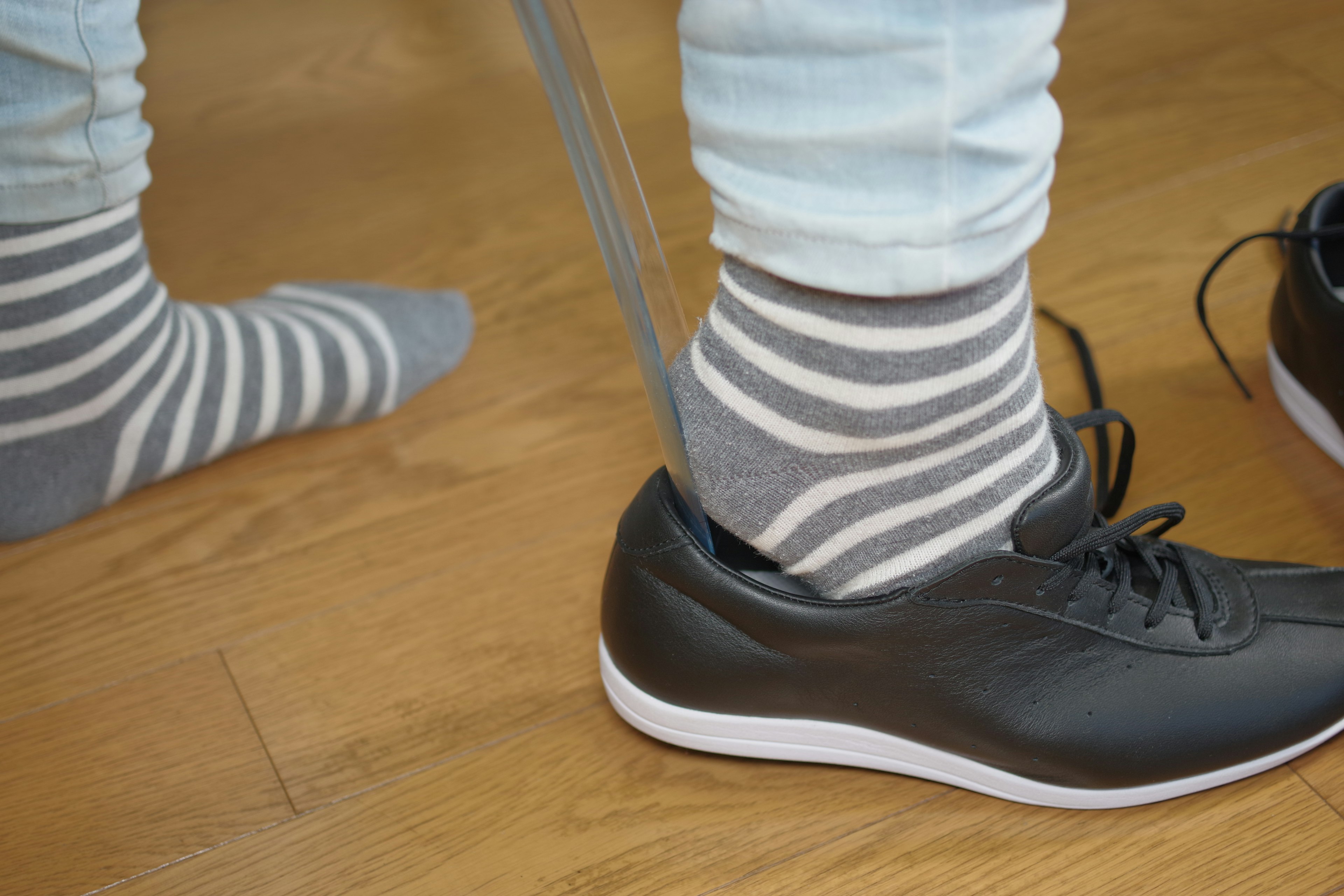 Image montrant un pied dans une sneaker noire et une chaussette rayée