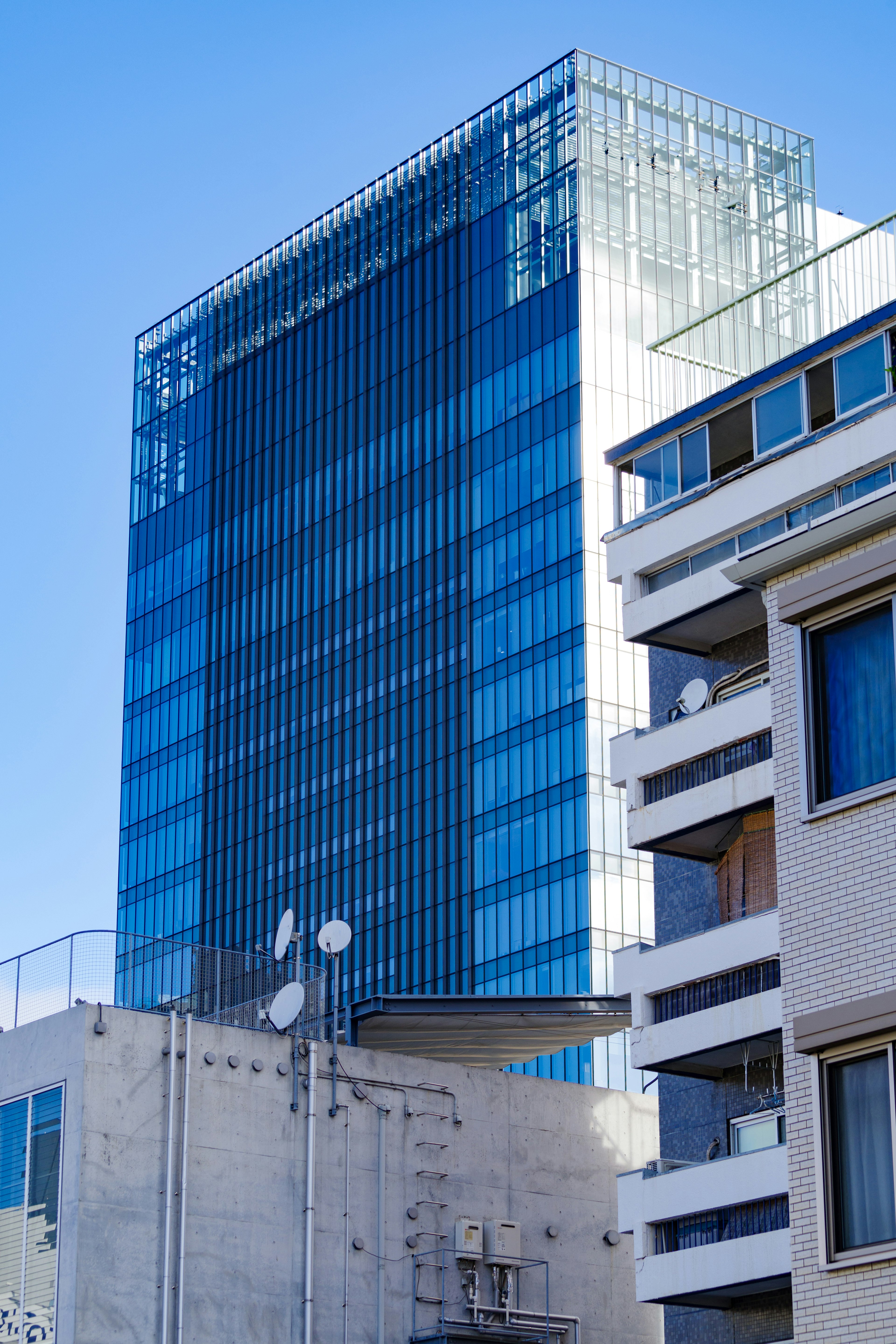 View of a modern blue glass skyscraper alongside a low-rise building