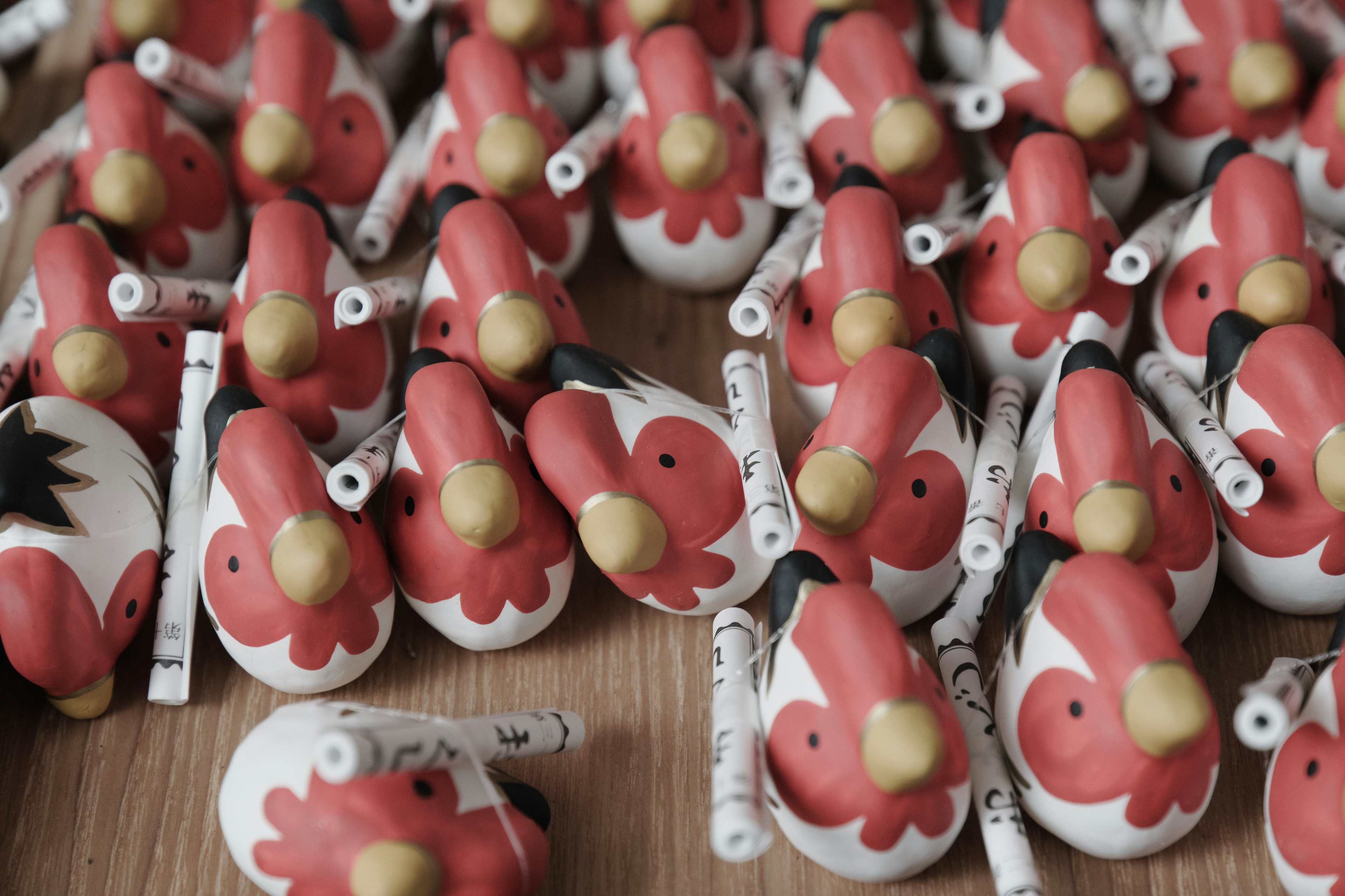 Numerous small bird figures with red heads and yellow beaks arranged closely together